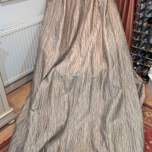 Large textured gray drape covering a bulky object in a living room, with a radiator on the left and a wine rack on the right.