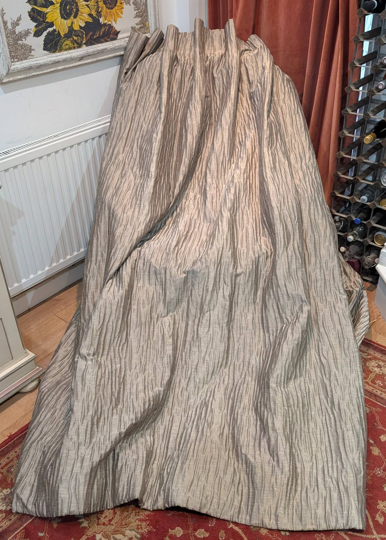 goblet1 - Divinely Vintage Interiors Large textured gray drape covering a bulky object in a living room, with a radiator on the left and a wine rack on the right.