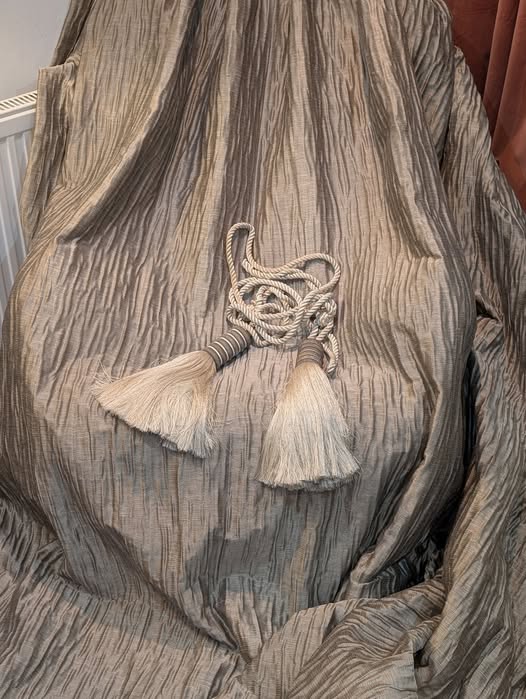 goblet7 - Divinely Vintage Interiors Gray textured fabric draped over a surface with a knotted white tassel cord and two tassels in front.