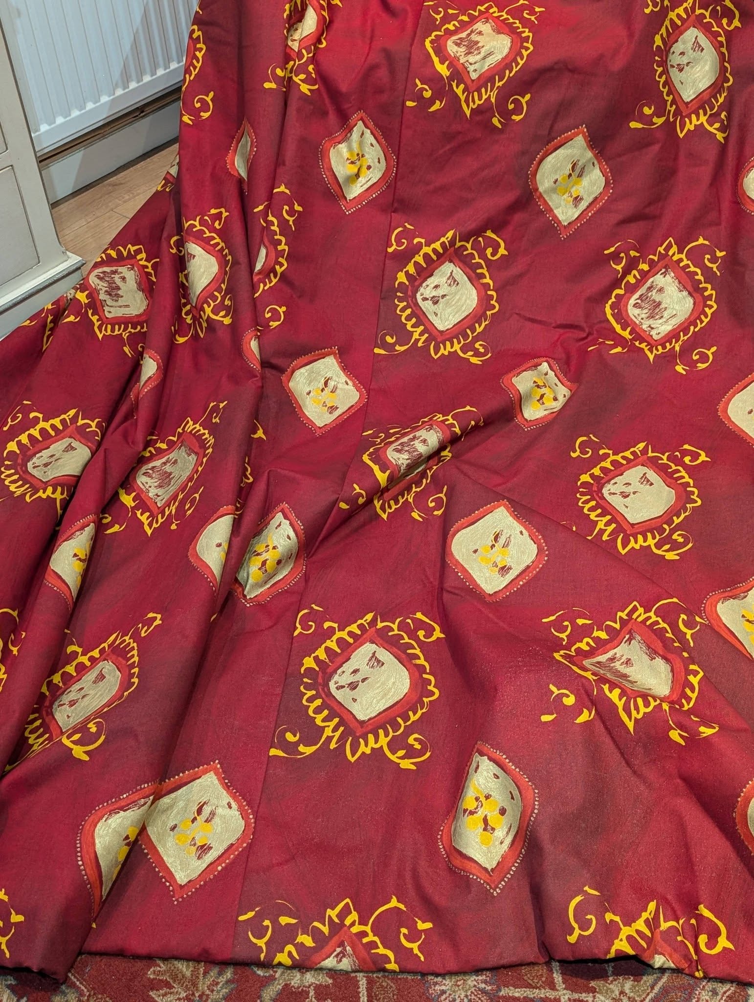 lauren2 - Divinely Vintage Interiors Decorative maroon fabric with gold-outlined diamond motifs containing cream centers, draped over a surface.