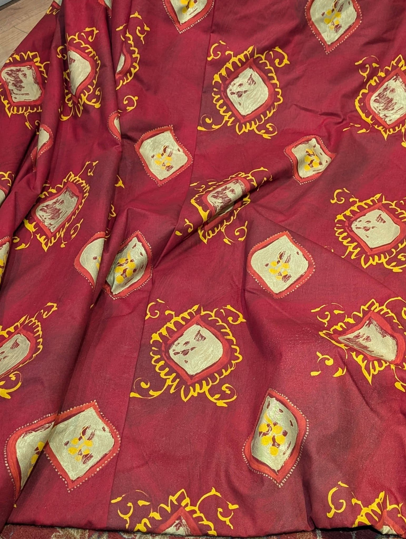 lauren4 - Divinely Vintage Interiors Maroon fabric with repeated beige square patches outlined in yellow and decorative swirls, forming a bold print pattern.