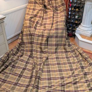 Large plaid-covered chair or sofa draped in beige and burgundy cloth in a cozy room.