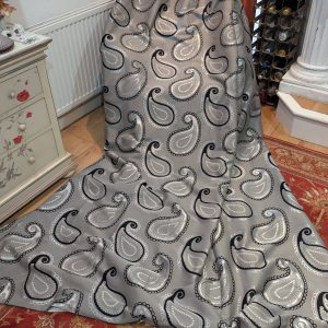 Gray paisley-patterned fabric draped over a dress form in a showroom or home decor store.