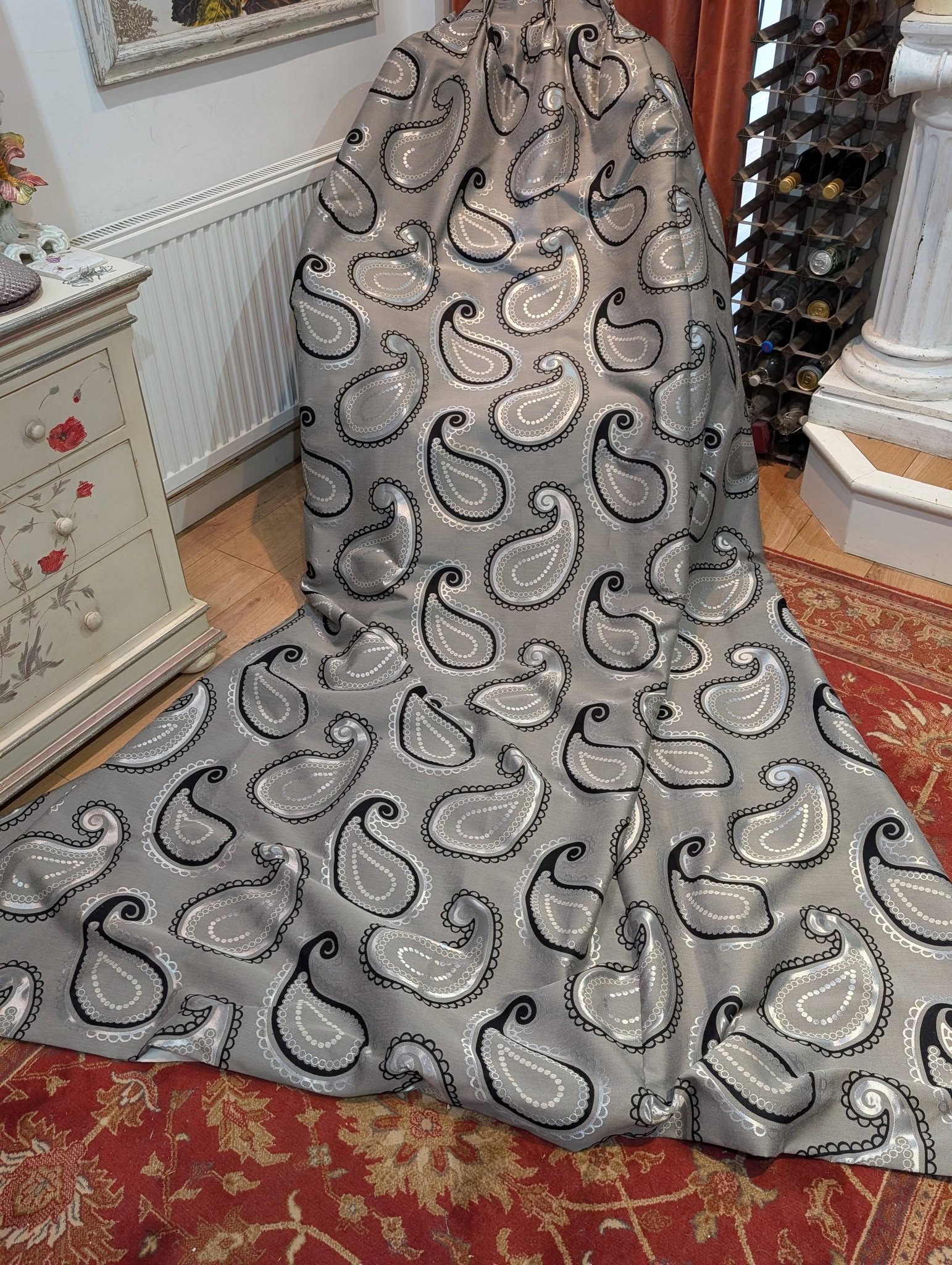 rach11 - Divinely Vintage Interiors Gray paisley-patterned fabric draped over a dress form in a showroom or home decor store.