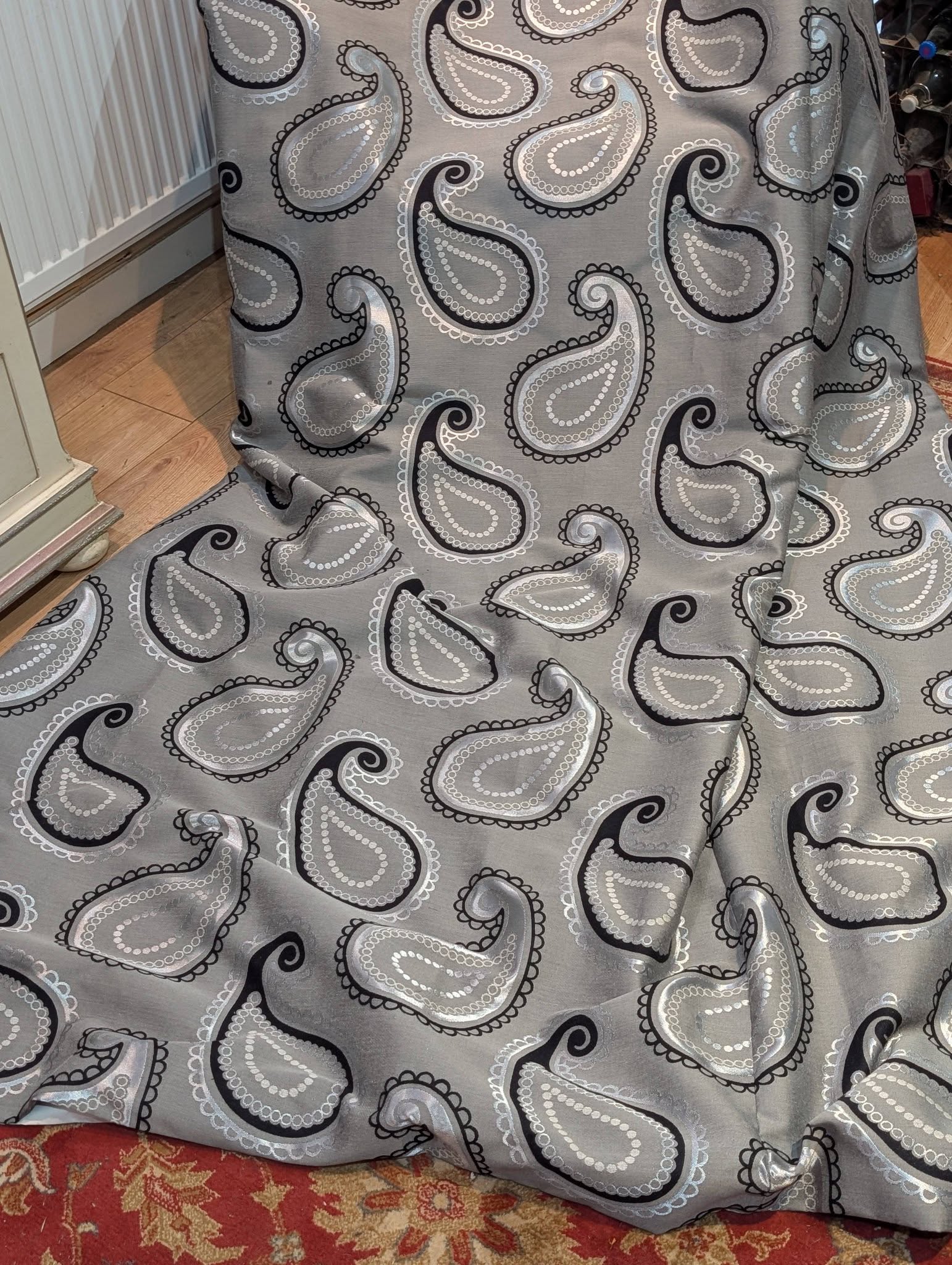 rach12 - Divinely Vintage Interiors Gray fabric with white and black paisley patterns draped over a surface, beside a radiator and wooden floor.
