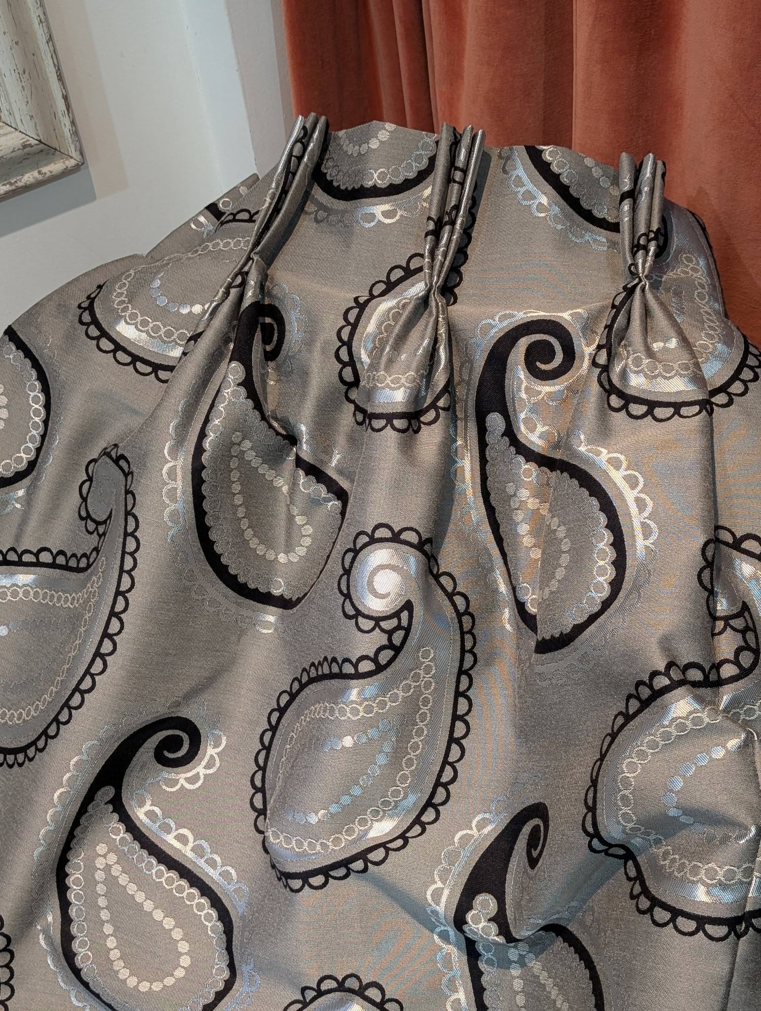 rach15 - Divinely Vintage Interiors Close-up of metallic grey fabric with black scalloped and circular lace-like patterns used decoratively or as a curtain material.