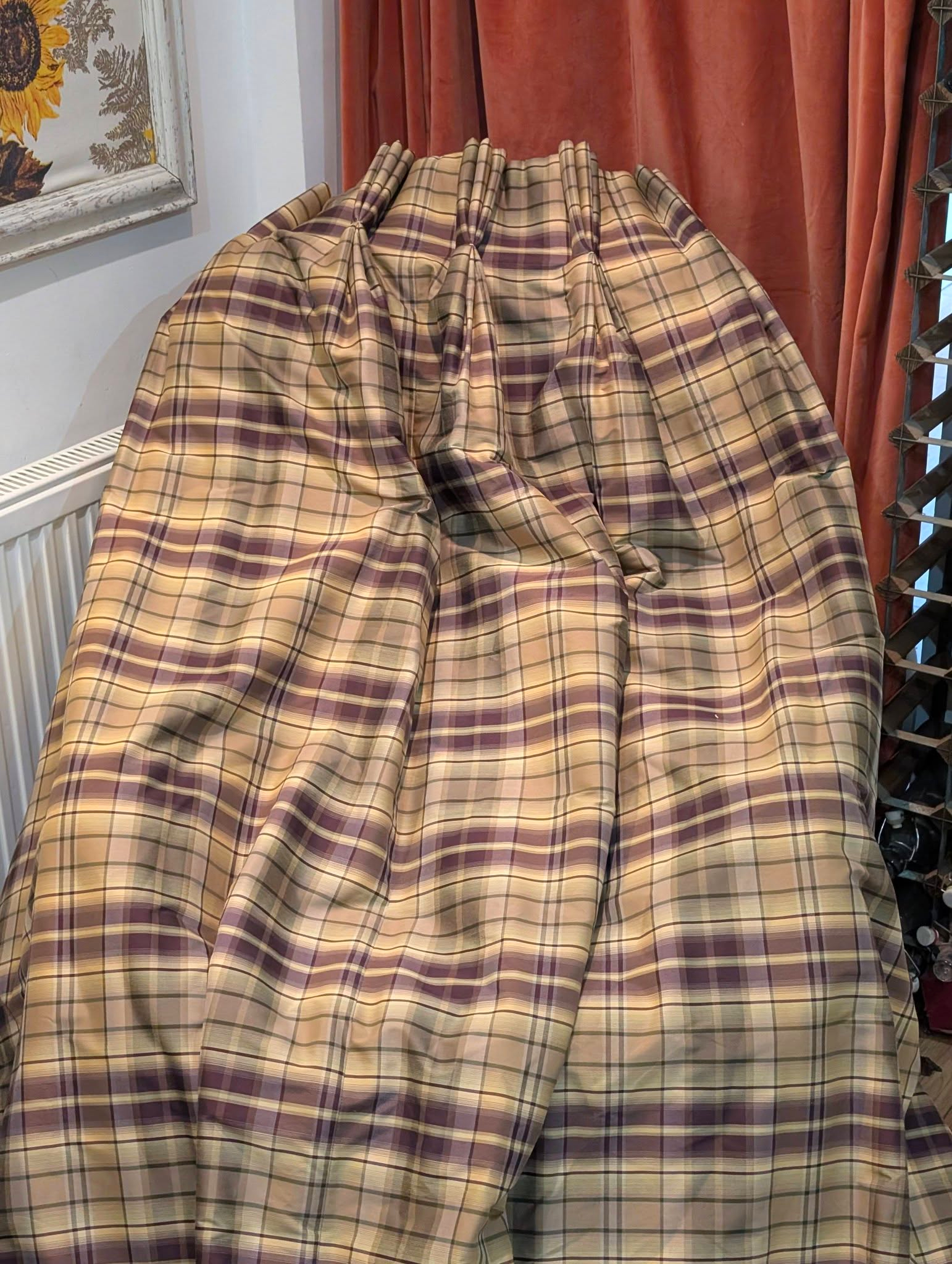rach3 - Divinely Vintage Interiors Beige and burgundy plaid fabric draped over a chair in a room with red curtains and a sunflower painting nearby.