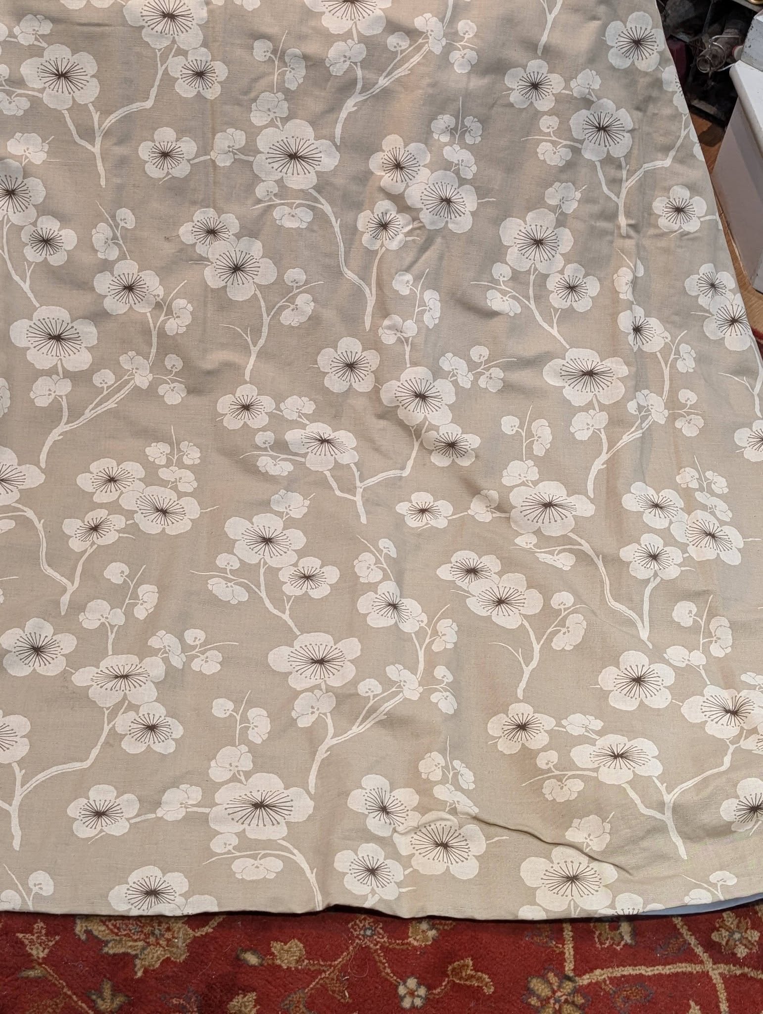 rach32 - Divinely Vintage Interiors Beige bedsheet with white floral pattern of branches and blossoms, a red patterned rug visible at the bottom edge.