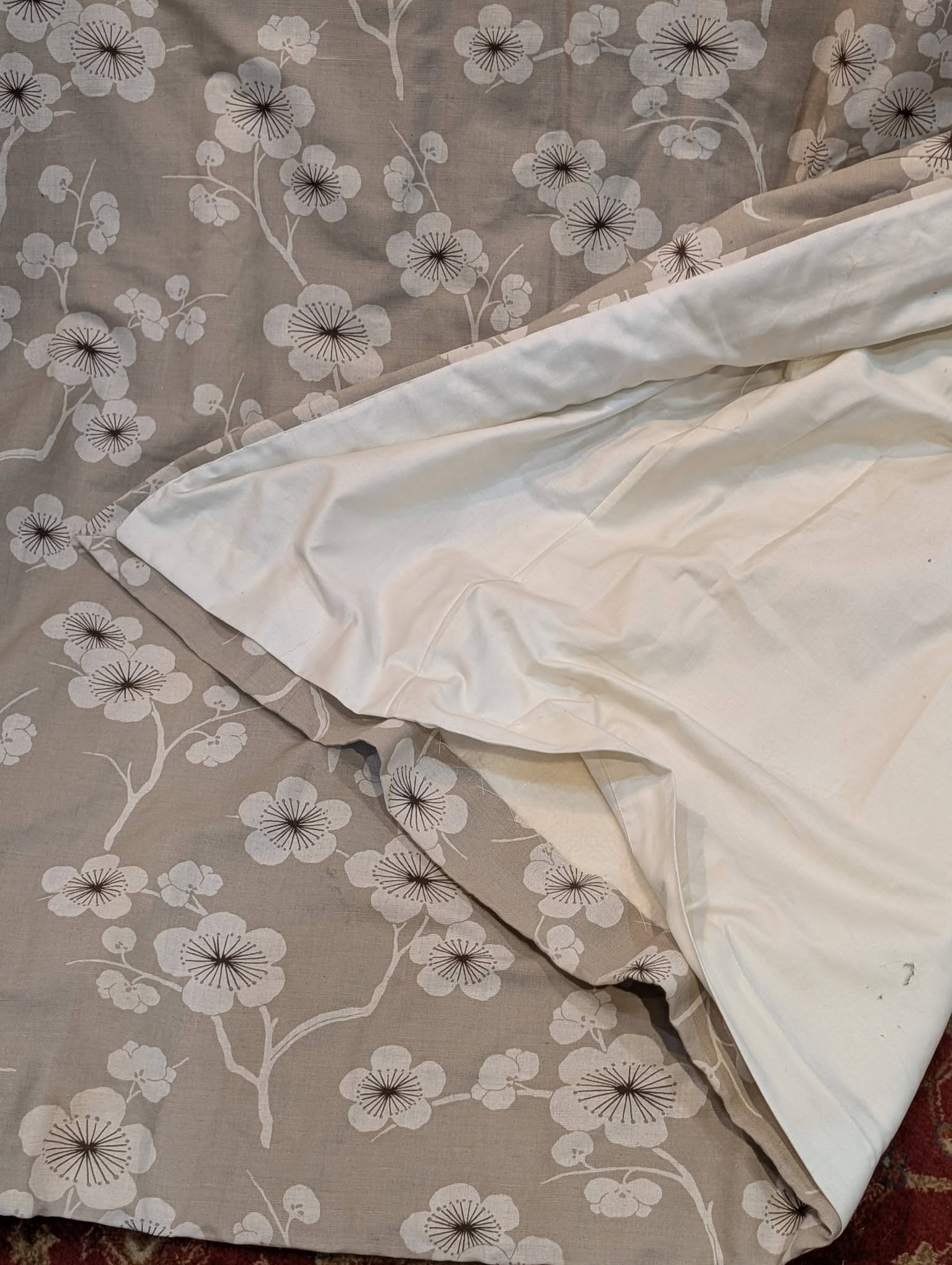 rach33 - Divinely Vintage Interiors Gray bedspread with white cherry-blossom pattern, folded white sheets laid on top.