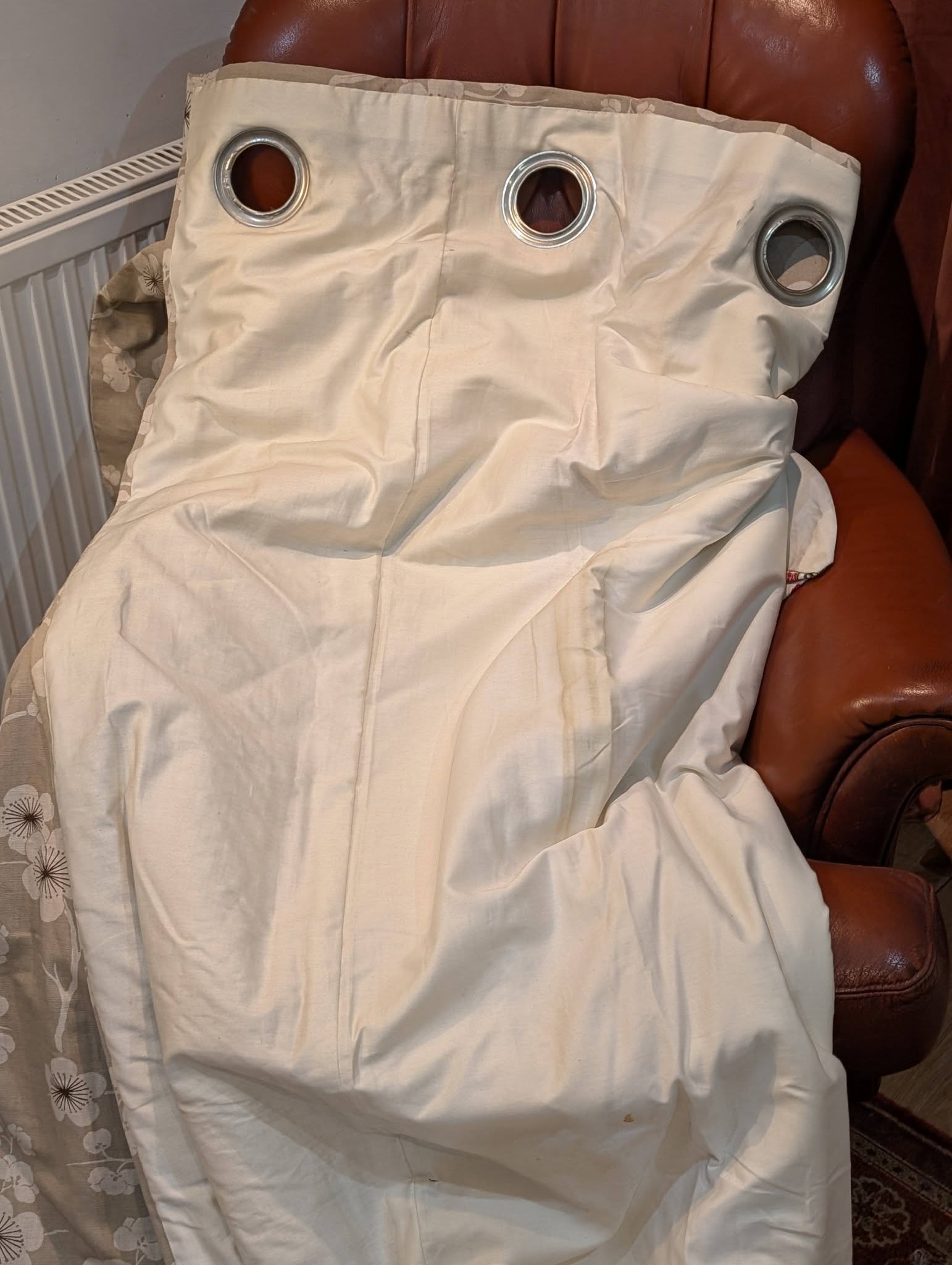 rach35 - Divinely Vintage Interiors Person seated on a brown chair wearing a white garment with three metal-ring eyelets on the chest area.