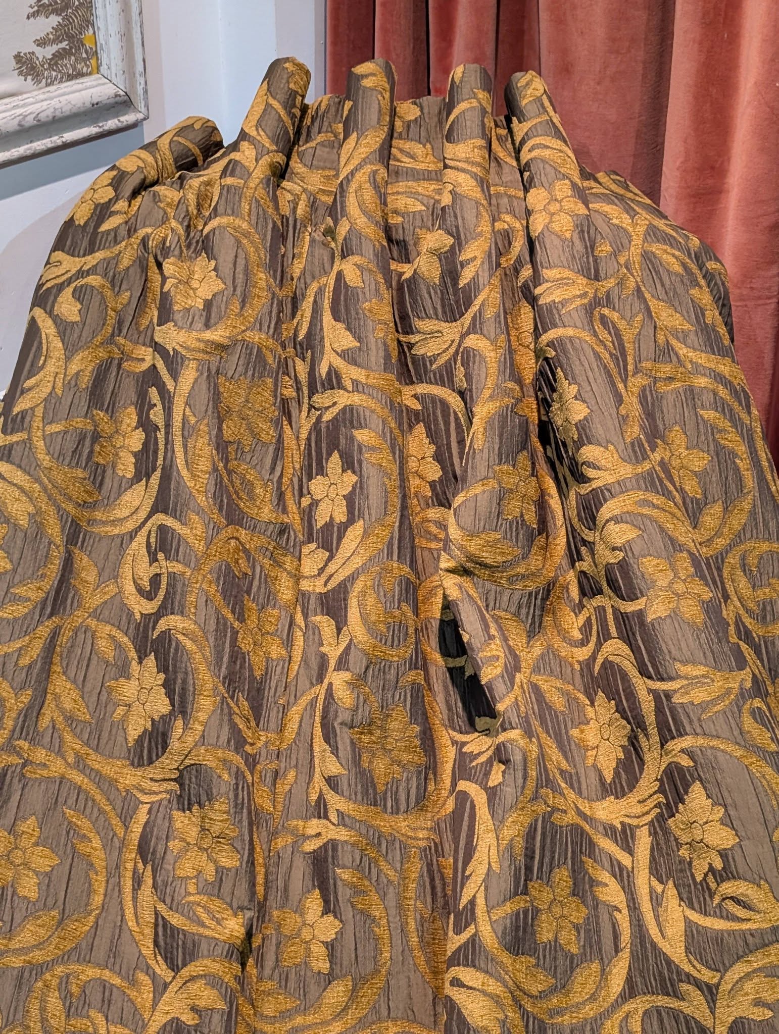 rachel3 - Divinely Vintage Interiors Gold floral-patterned fabric with gray background, draped in pleats against a pink curtain.
