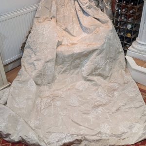 Beige floral chair cover draped over a chair in a room, with a wine rack to the right and a radiator on the left.