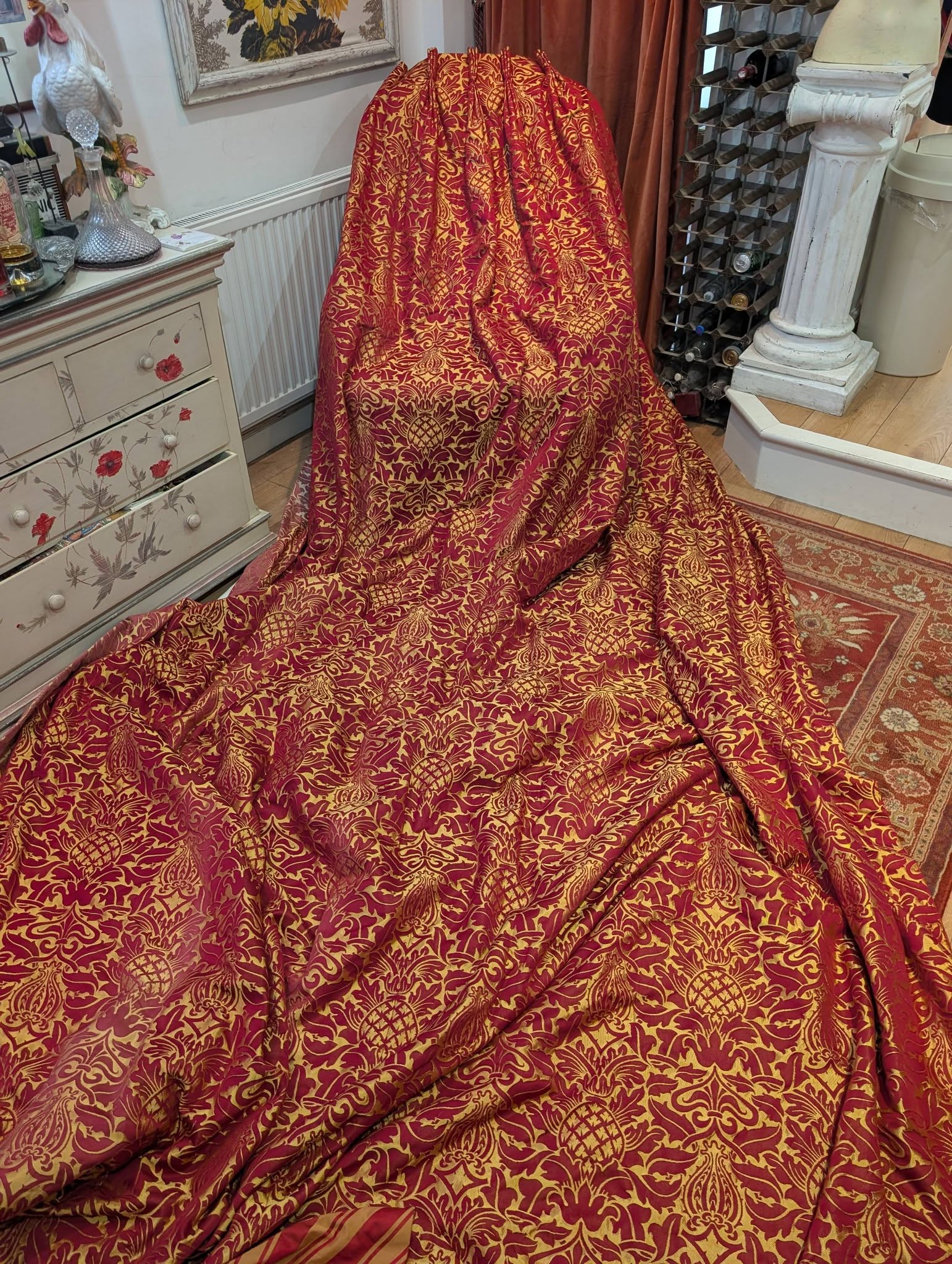 rich11 - Divinely Vintage Interiors Red and gold damask fabric draped over an object, pooling on the floor in a vintage-style room.