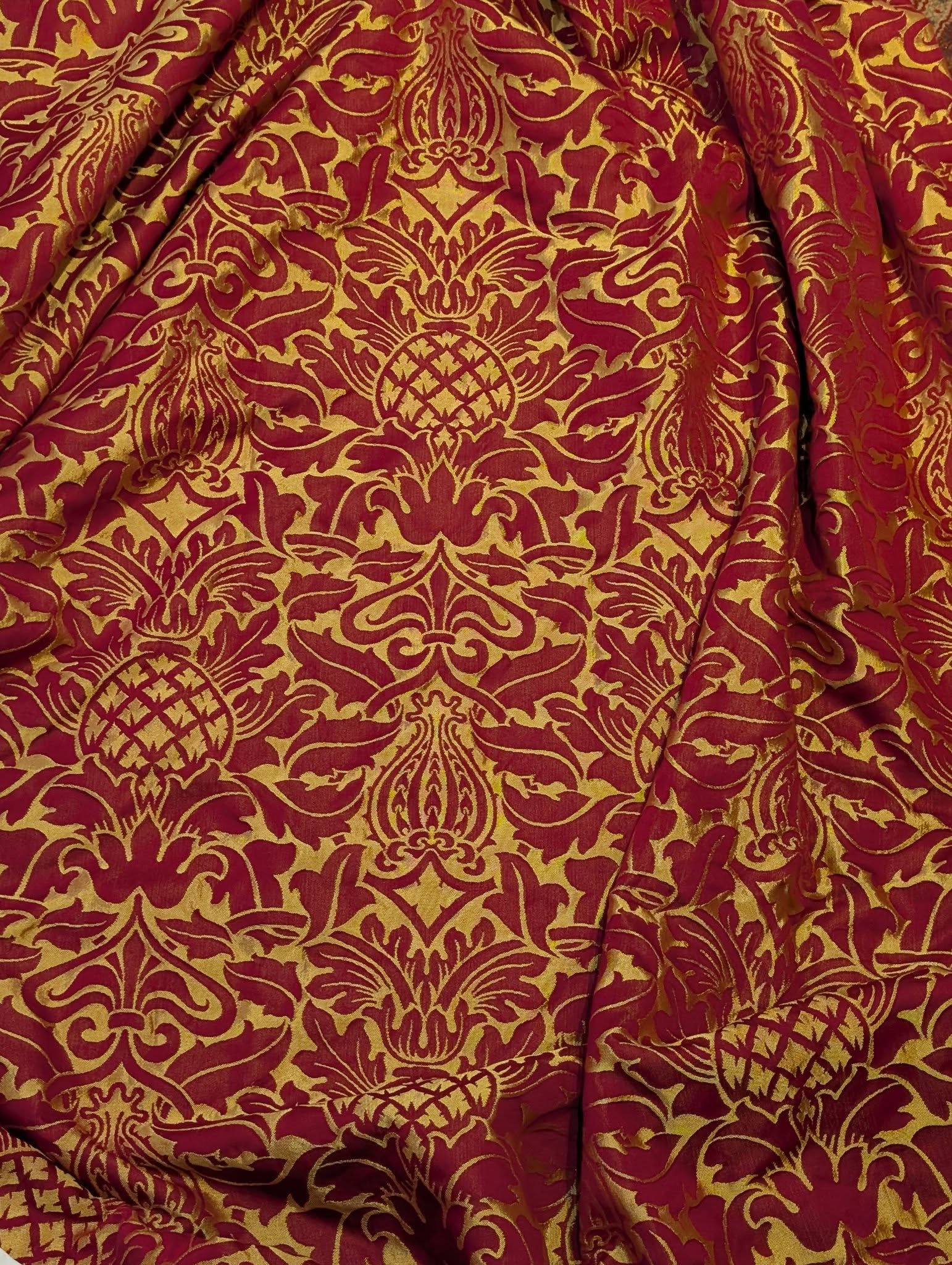 rich13 - Divinely Vintage Interiors Close-up of red and gold damask fabric with ornate floral patterns.