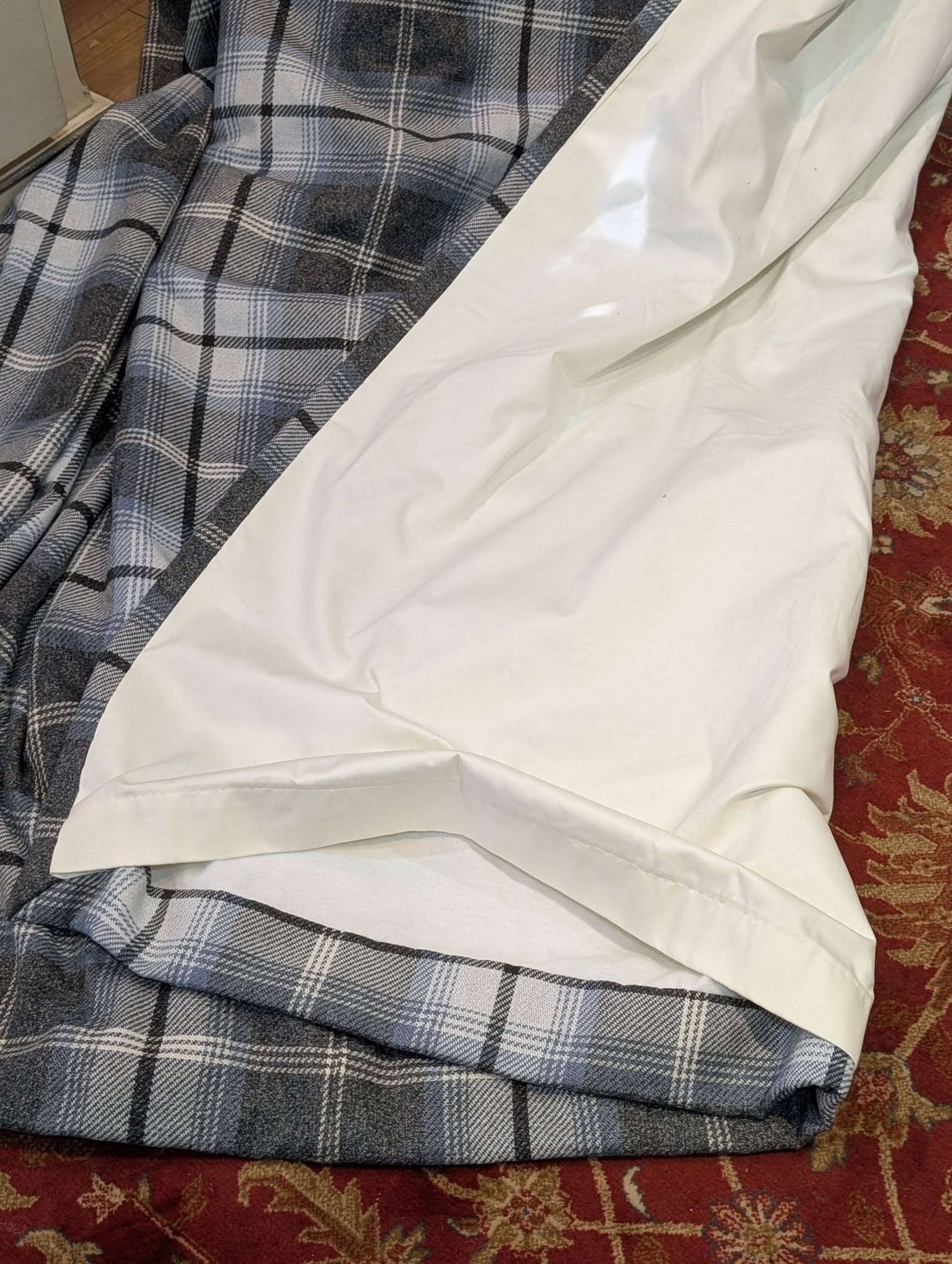 richard4 - Divinely Vintage Interiors Blue-gray plaid blanket draped over a chair with a white sheet partially covering it on a red patterned carpet.