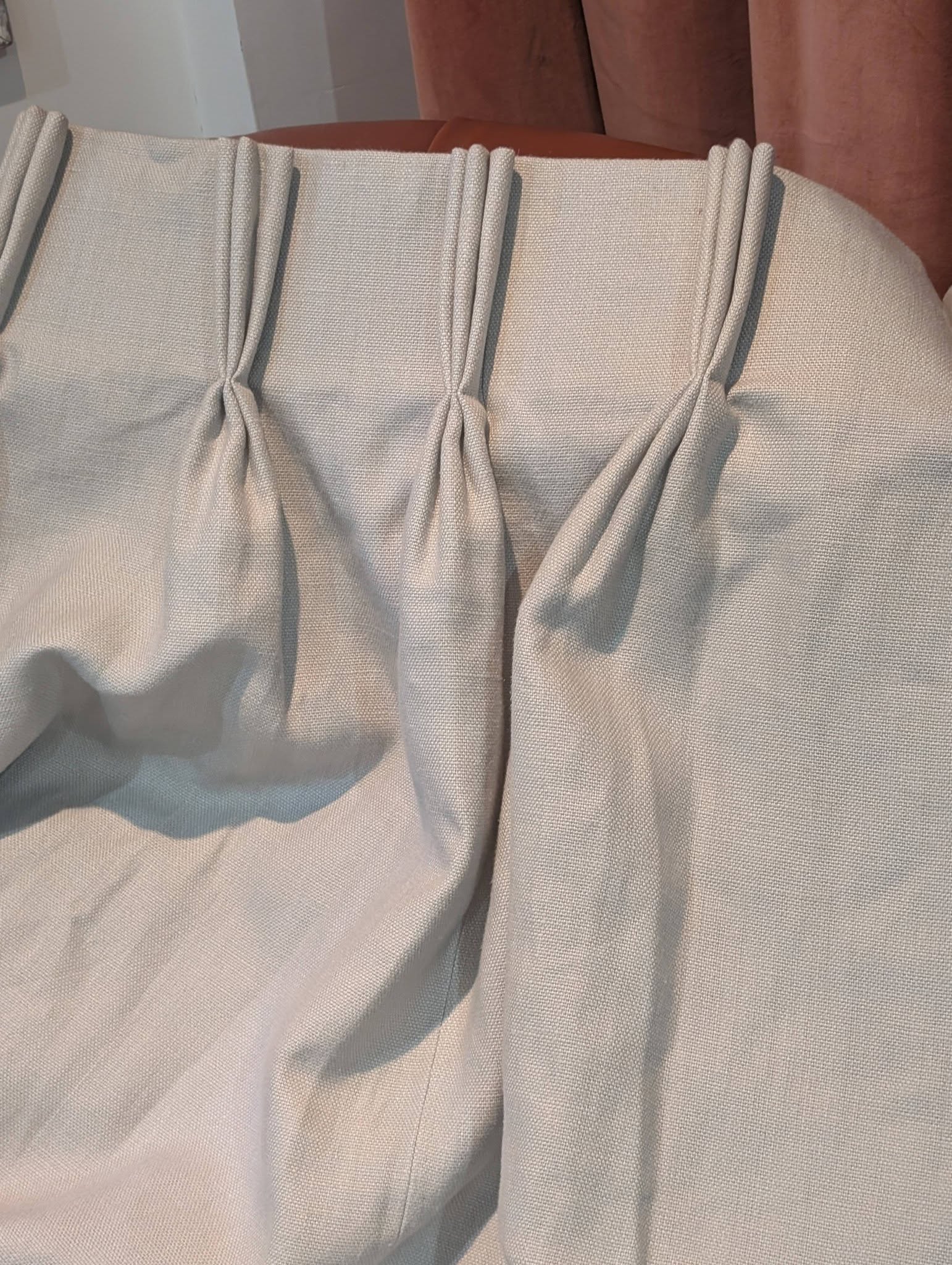 hannah15 - Divinely Vintage Interiors Close-up of light gray woven fabric with vertical pleats and soft folds, likely drapery or upholstery.