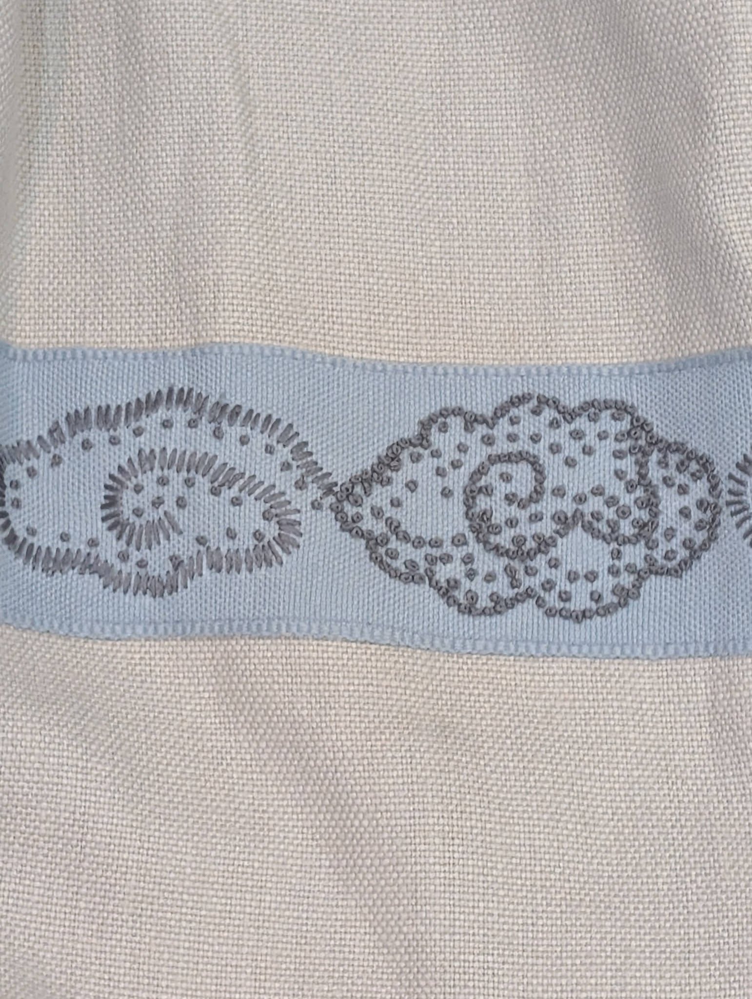 hannah17 - Divinely Vintage Interiors Close-up of light beige woven fabric with a pale blue decorative band featuring circular bead embroidery patterns at the bottom edge.