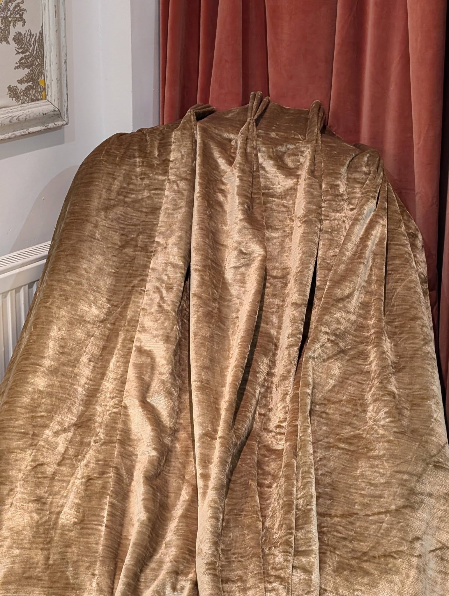 judith3 - Divinely Vintage Interiors Crushed velvet brown drapery covering a large object in a room, with pink curtains behind and a radiator to the left.