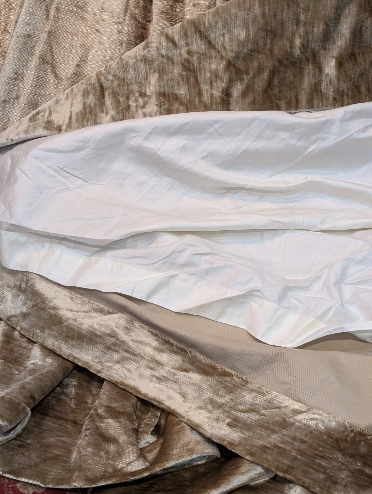 judith4 - Divinely Vintage Interiors Close-up of wrinkled brown velvet fabric layered over white sheets, showing folds and texture.
