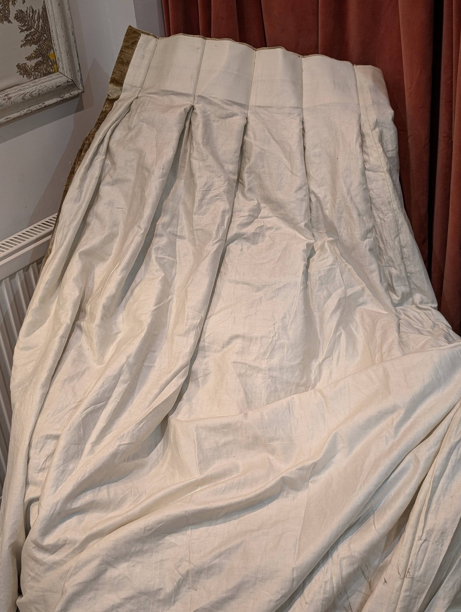 judith6 - Divinely Vintage Interiors White wrinkled fabric draped over an object in a room, with brown curtains behind it and part of a framed frame visible on the left.
