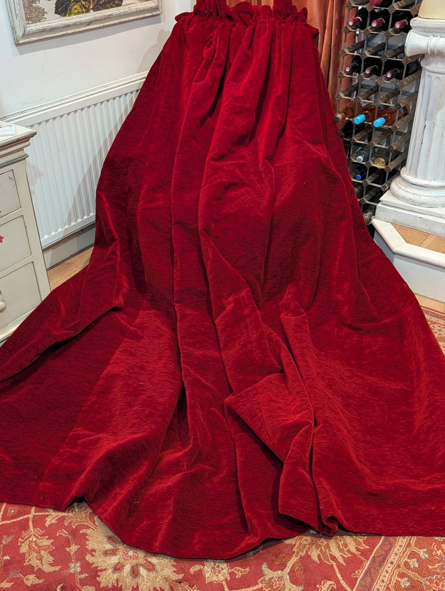 red2 - Divinely Vintage Interiors Red velvet drape covering a large object in a room, with a wine rack and radiator visible.