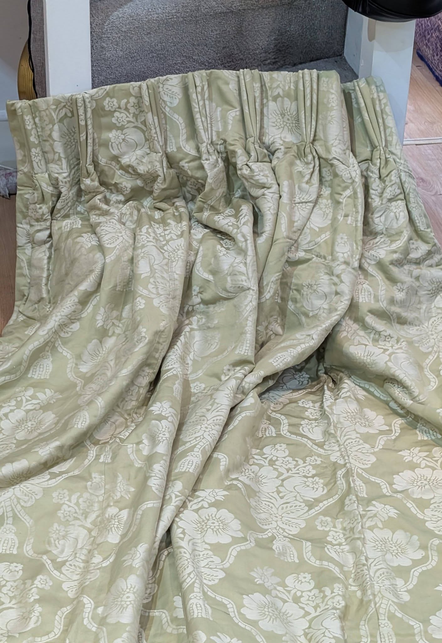 bed3 - Divinely Vintage Interiors Light green quilt with large white floral pattern draped over a surface, creased and gathered at the top edge.