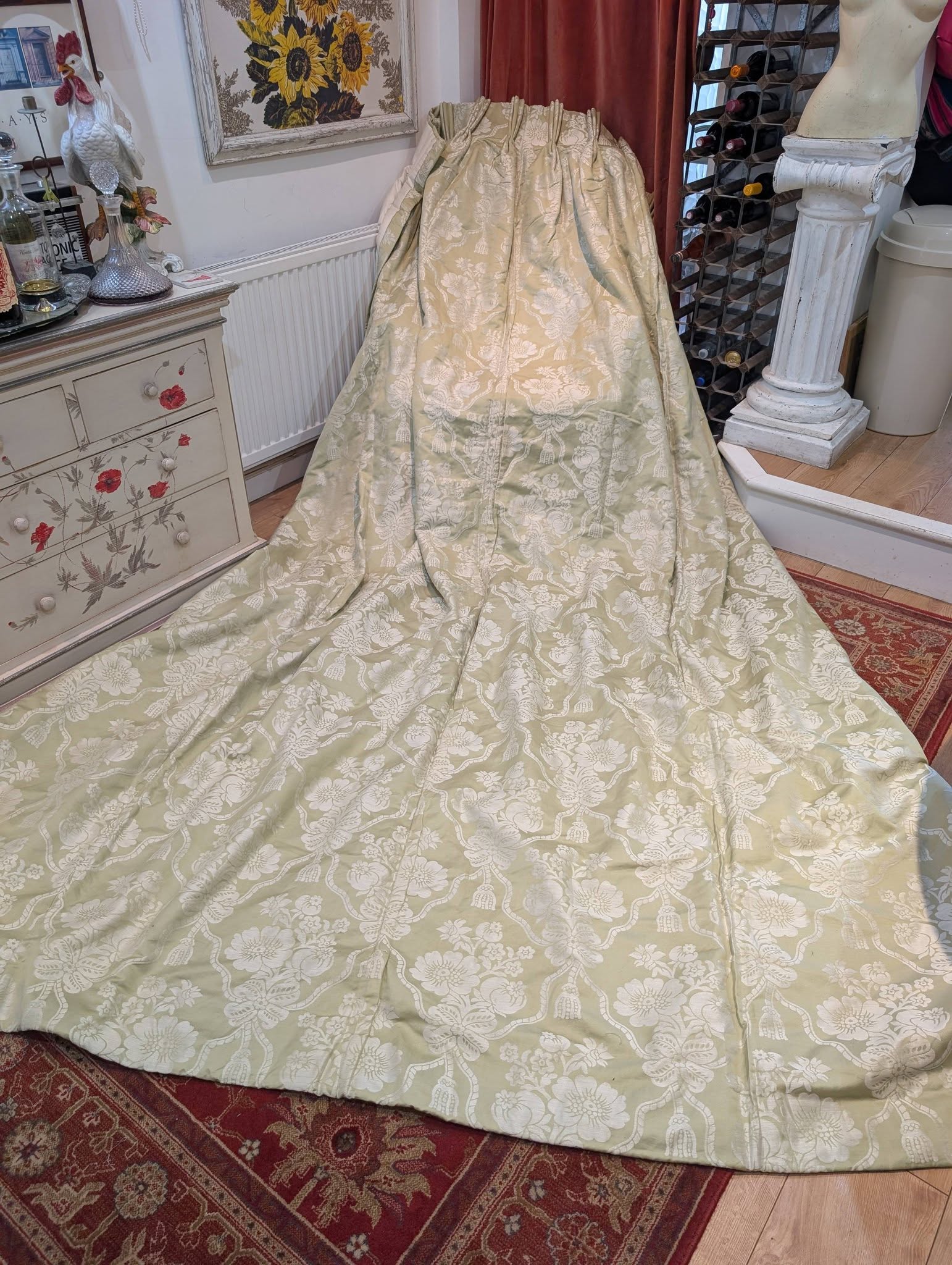 bed9 - Divinely Vintage Interiors Pale green damask fabric draped over a standing form, creating a floor-length display in a vintage-styleVery Long Linen Damask Pinch Pleat Second-Hand Curtains – 2 Pairs Available.