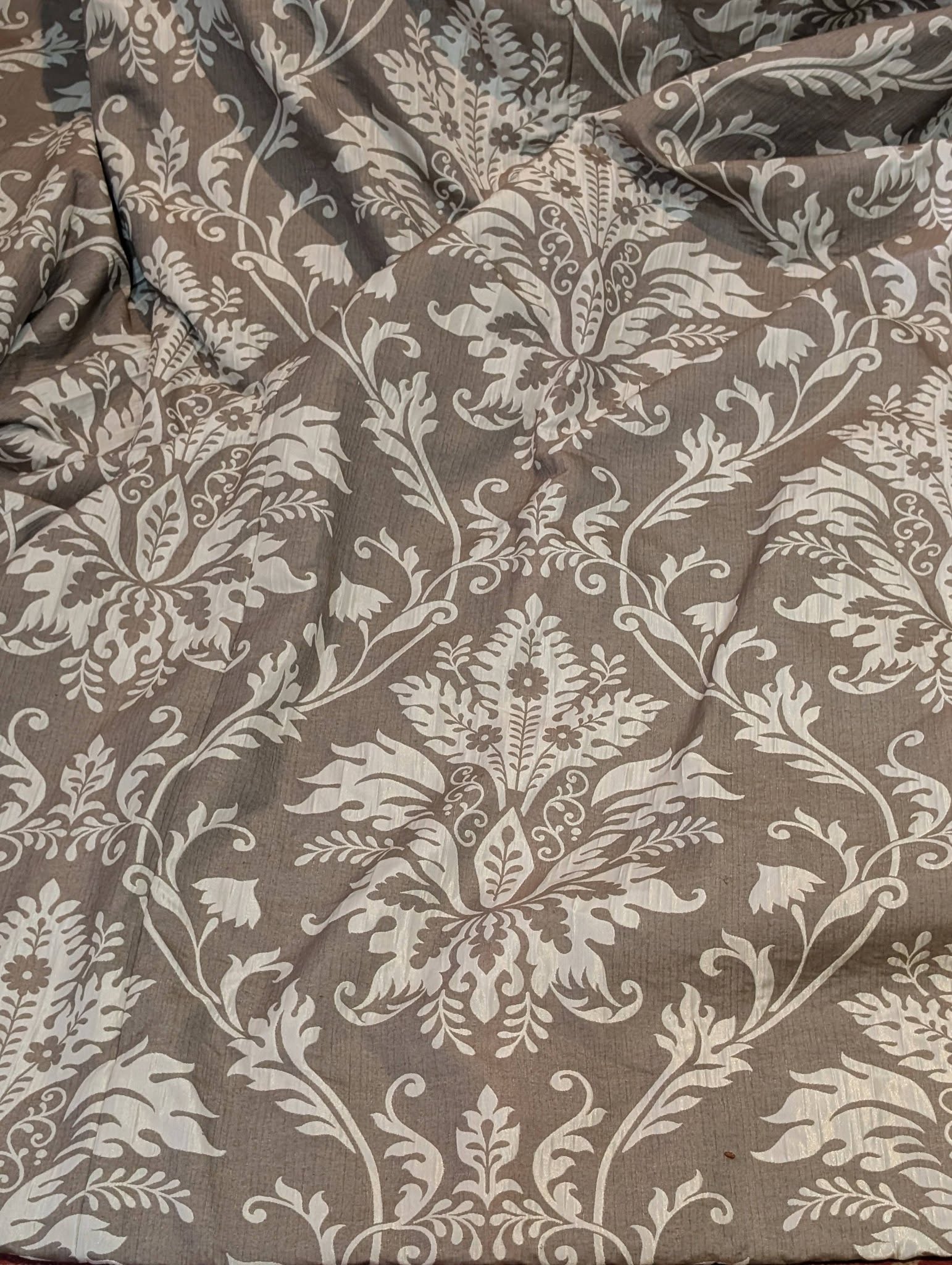 cream2 - Divinely Vintage Interiors Damask-patterned bedspread in taupe and ivory with scrolling floral motifs on a gray-brown background, laid flat.