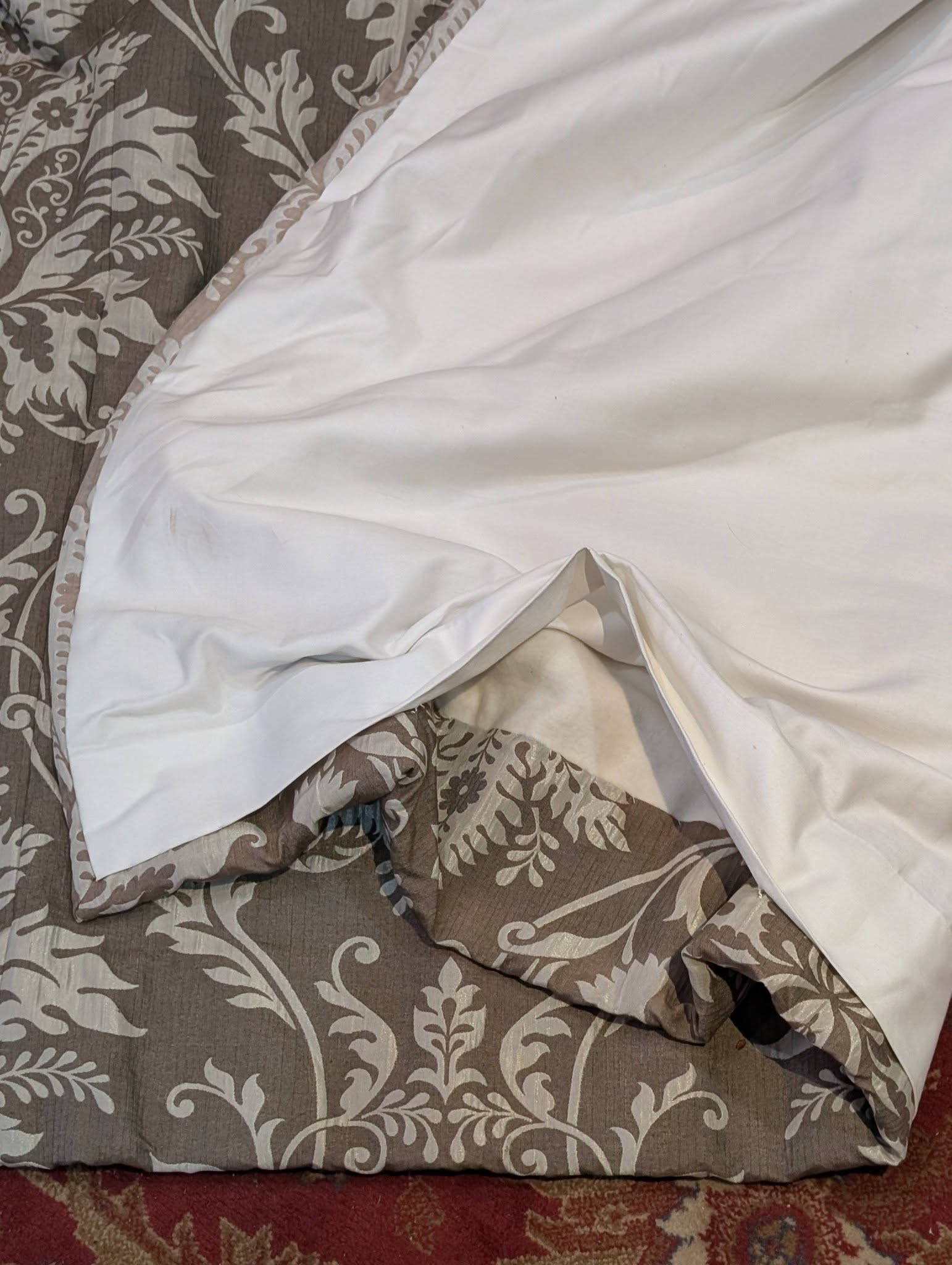 cream4 - Divinely Vintage Interiors White bedsheet and a crumpled duvet spread over a brown floral-patterned bedspread.