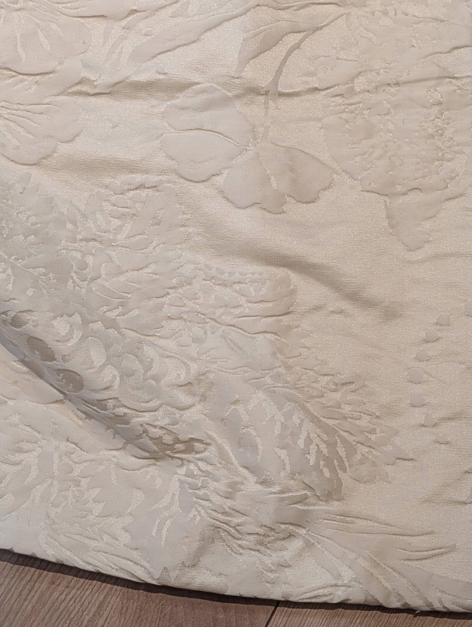 dam2 - Divinely Vintage Interiors Close-up of a cream damask fabric with a raised floral pattern.