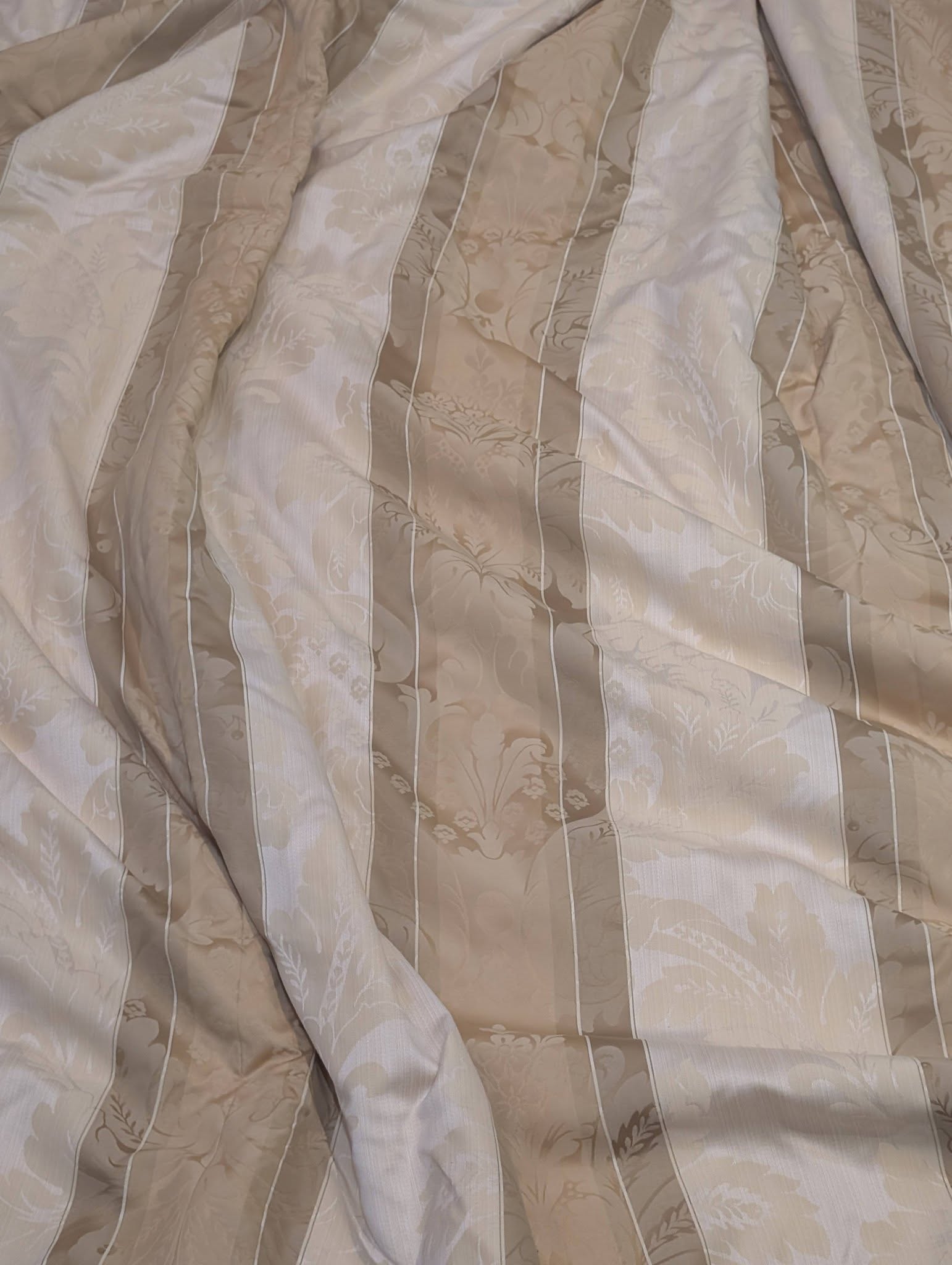 dam2 - Divinely Vintage Interiors Beige bedspread with vertical stripes and a floral damask pattern, crumpled and wrinkled across the bed.
