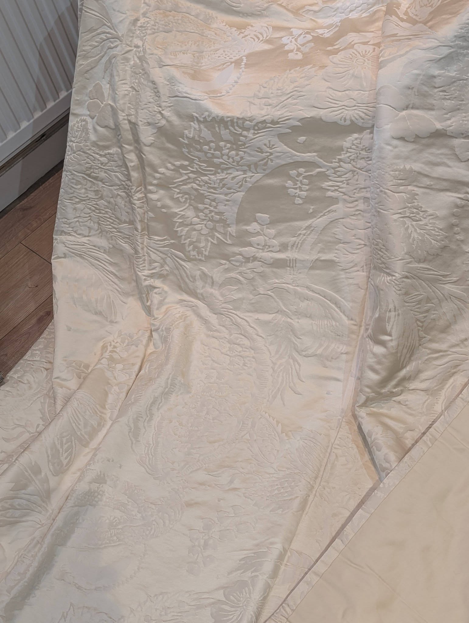 dam5 - Divinely Vintage Interiors Cream-colored quilt with a raised floral damask pattern draped on a bed.