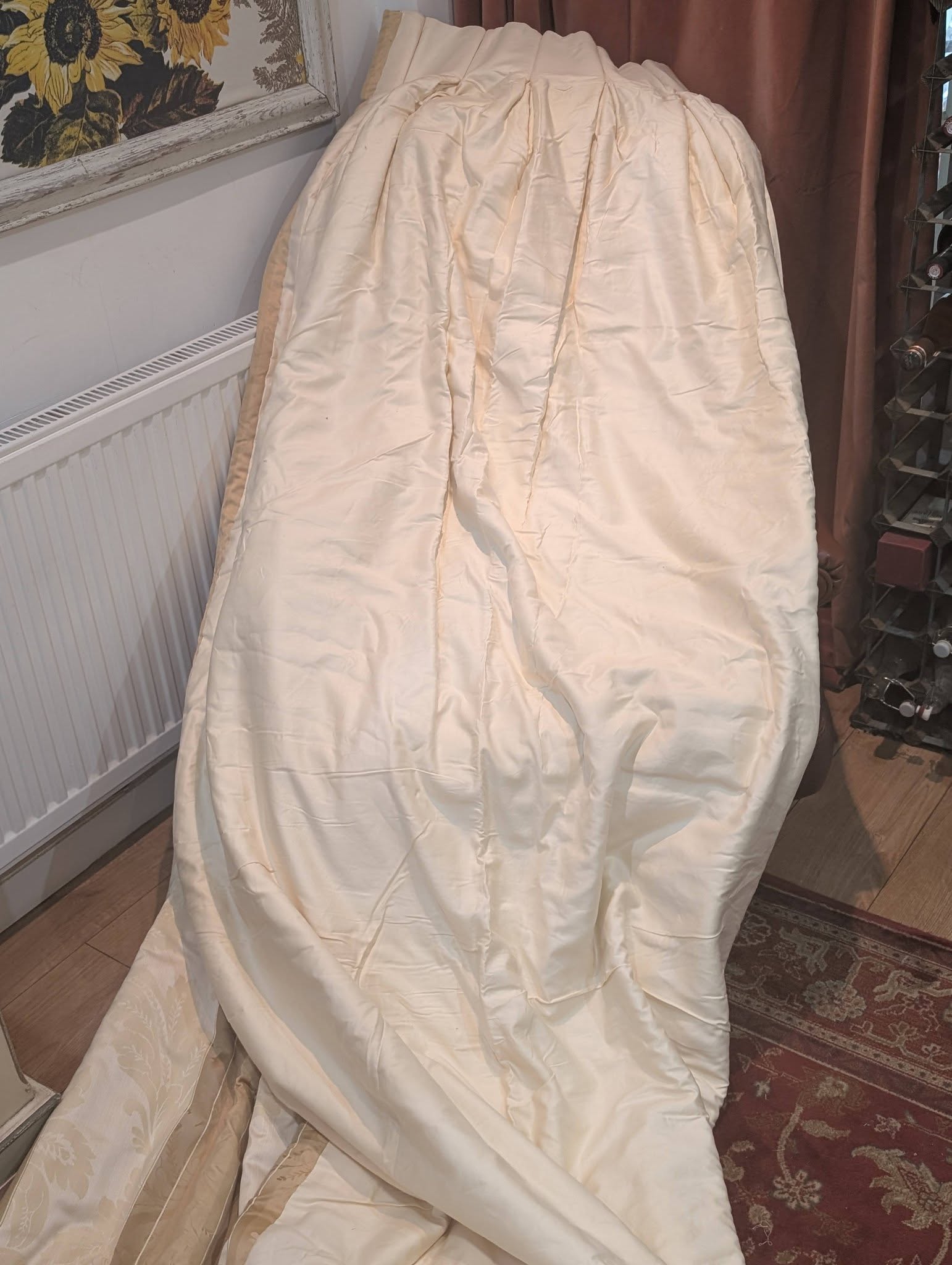 dma7 - Divinely Vintage Interiors Large cream satin sheet or cover draped over an object in a living room, with a sunflower painting on the wall nearby.