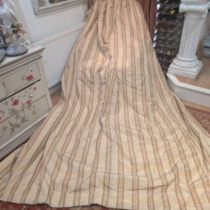 Beige plaid fabric draped over furniture in a vintage-styled room with a sunflower painting and wine rack nearby.