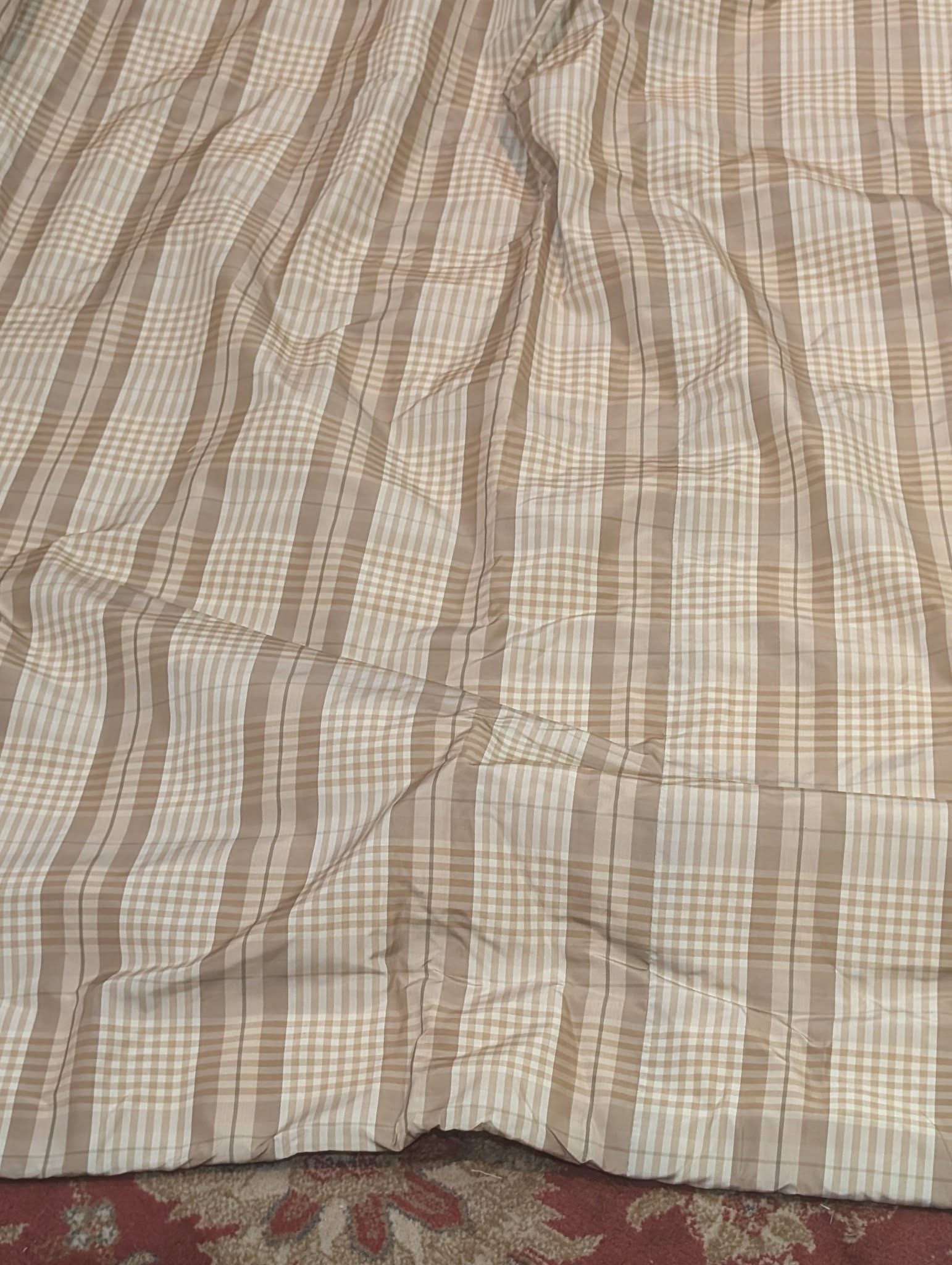 ging2 - Divinely Vintage Interiors Beige plaid bedspread covering a bed and touching a patterned carpet at the foot of the bed.