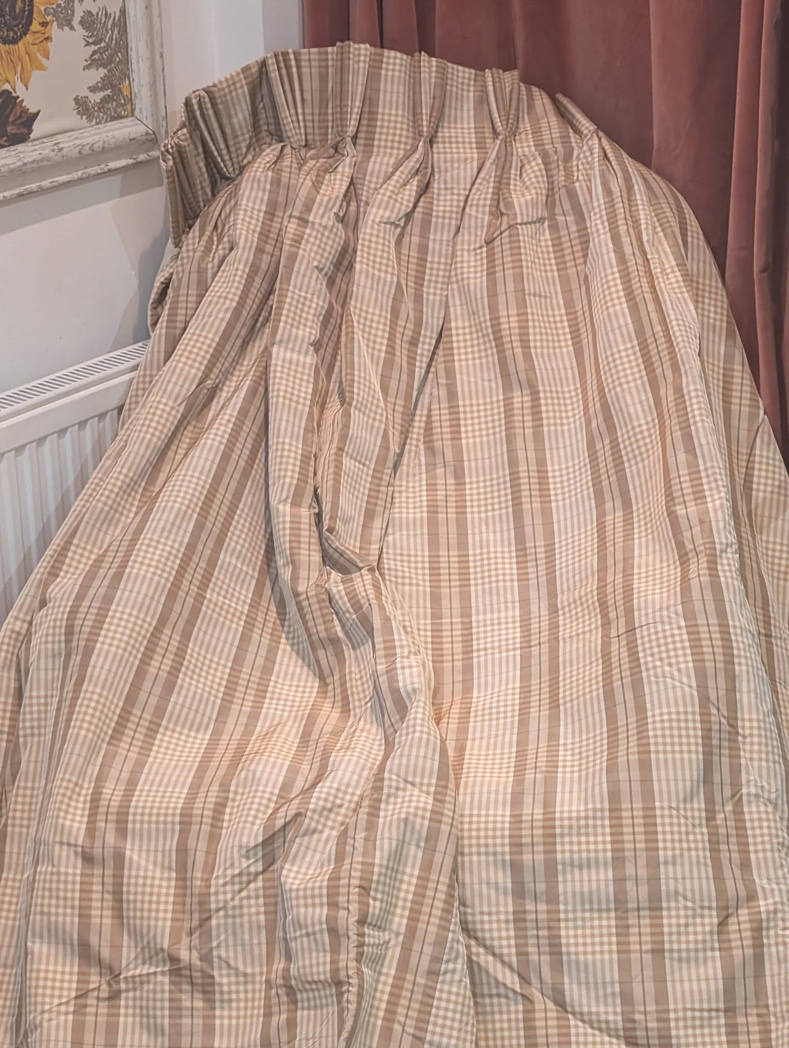 ging3 - Divinely Vintage Interiors Beige plaid fabric draped over a chair in a corner, near a radiator and brown curtains.