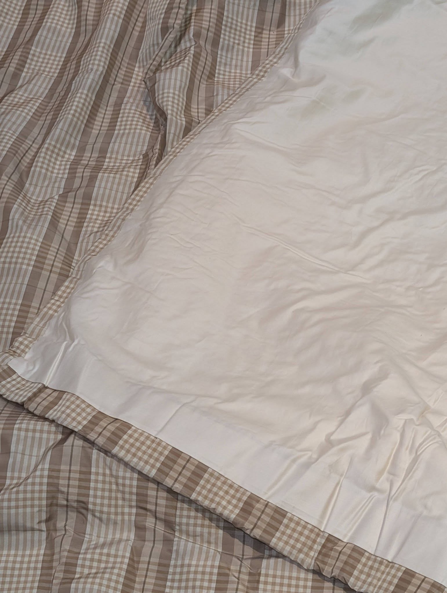ging4 - Divinely Vintage Interiors Close-up of a rumpled bed with beige plaid sheets and a white duvet overlapping them