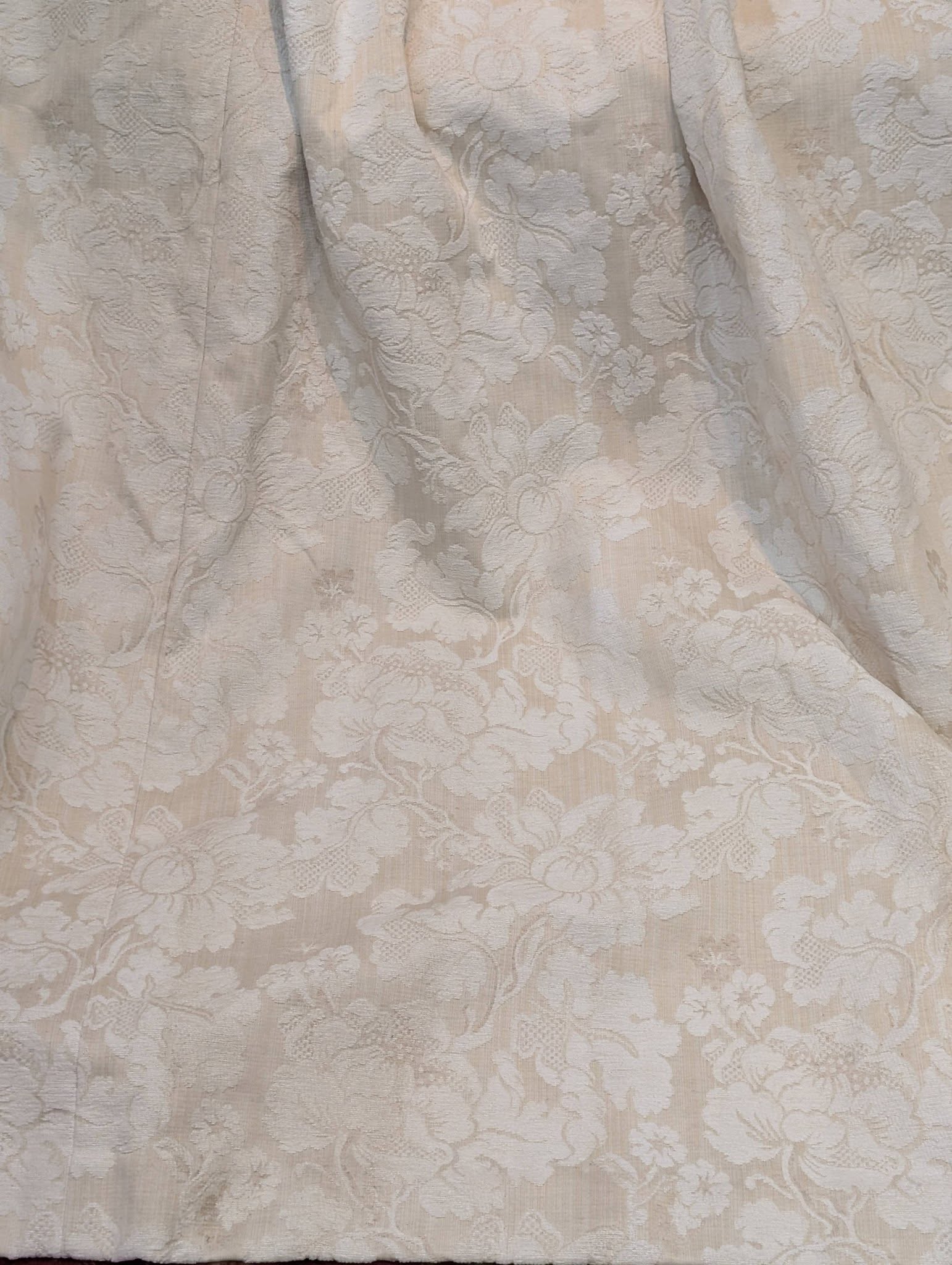 leila5 - Divinely Vintage Interiors Beige lace fabric with a floral damask pattern, draped and wrinkled in places.