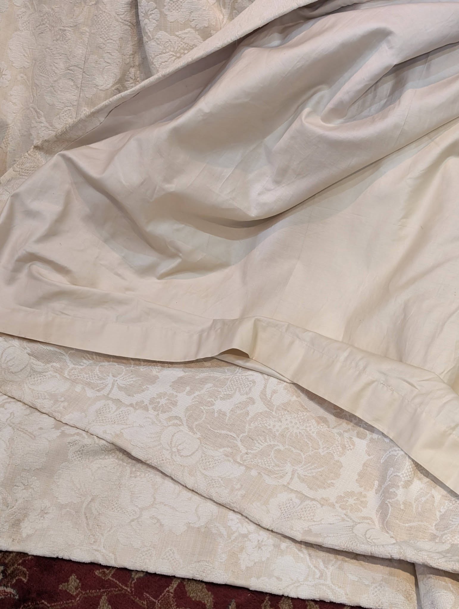 leila6 - Divinely Vintage Interiors Close-up of layered white bed linens: smooth sheets atop a patterned lace bedspread.