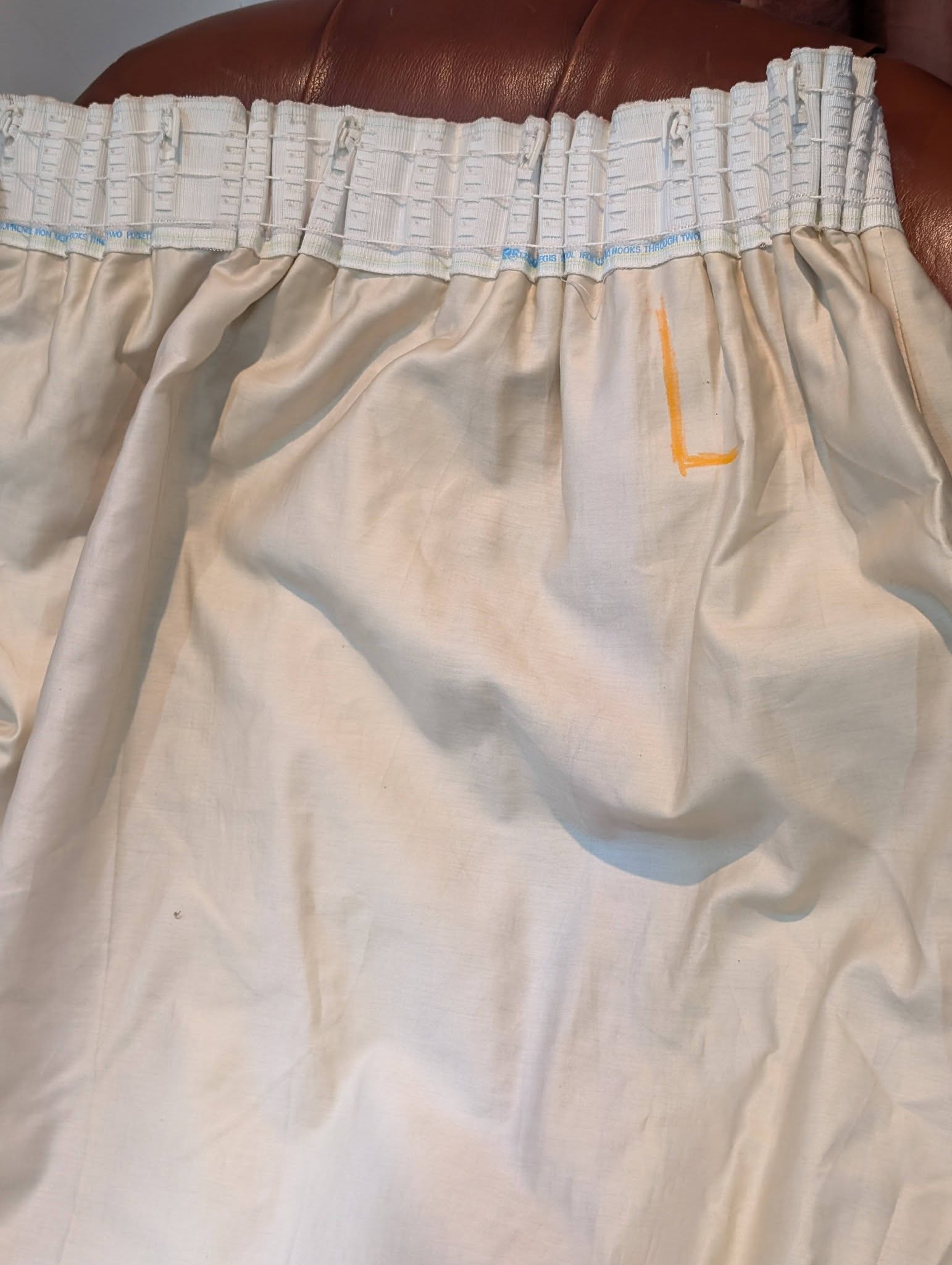 leila8 - Divinely Vintage Interiors Close-up of a white fabric sheet with an elastic gathered edge at the top; a small orange L-shaped mark is visible on the fabric.