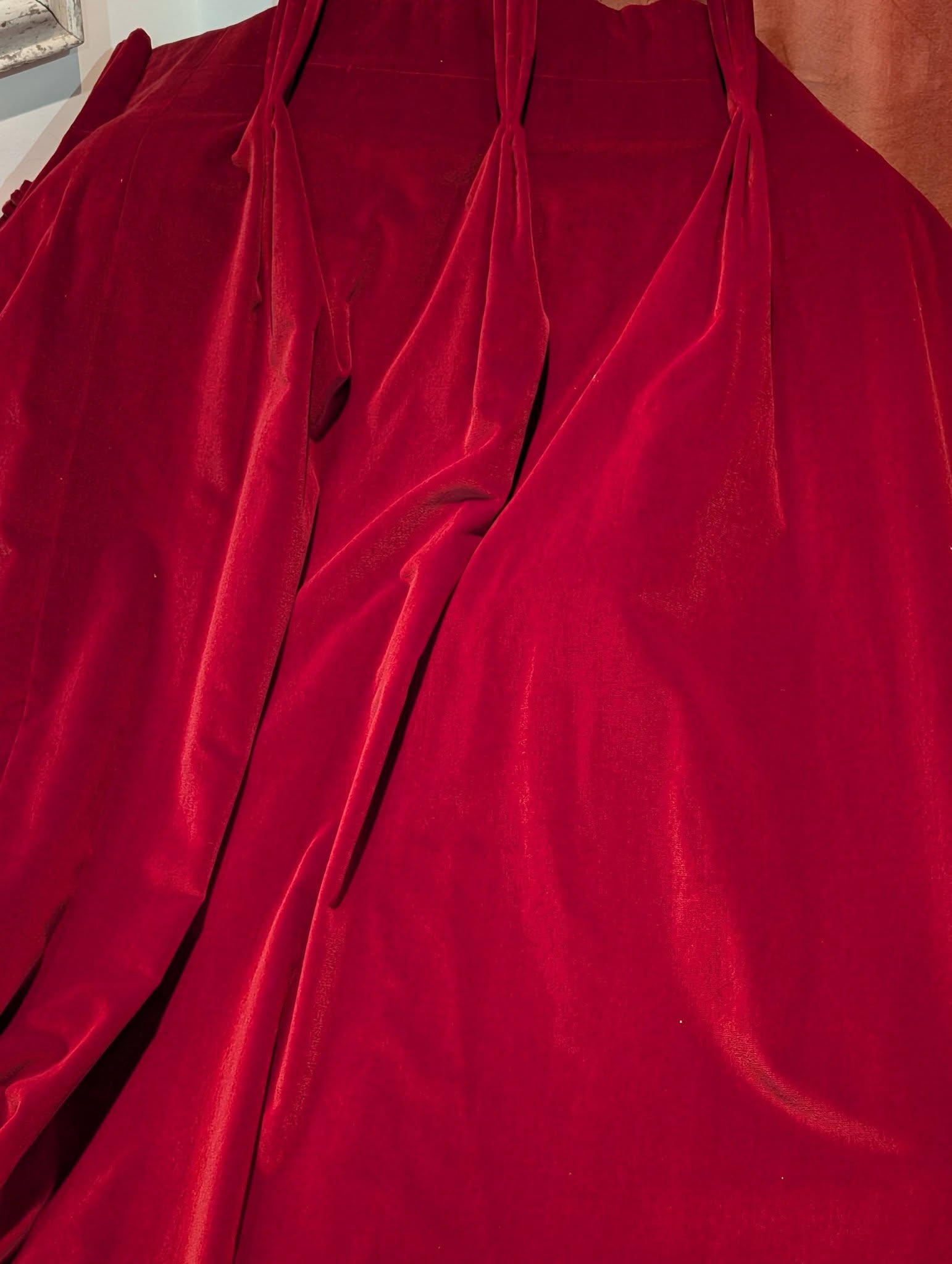 Close-up of deep red velvet fabric with soft folds and draped gathers