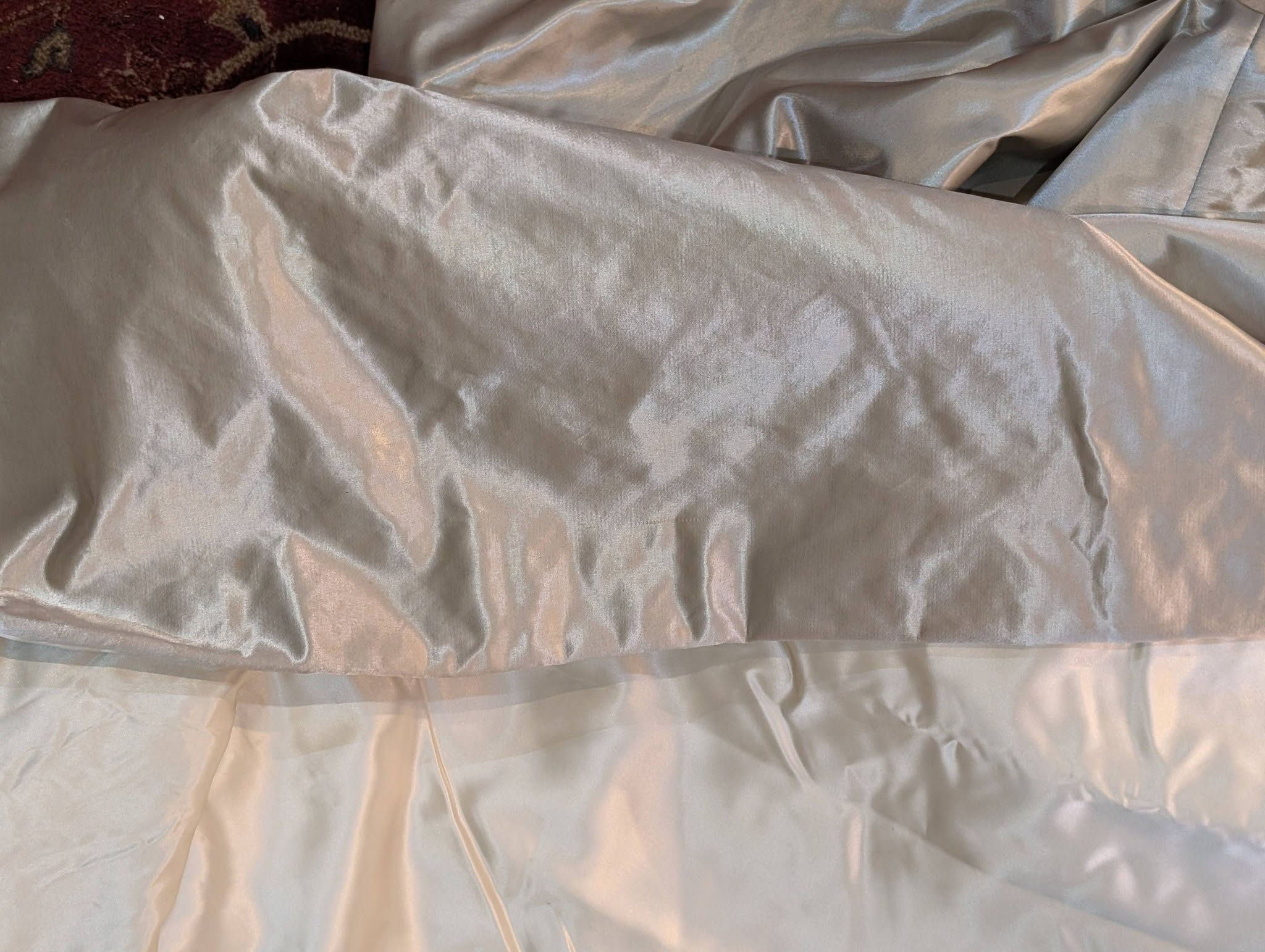 silk11 - Divinely Vintage Interiors Close-up of light gray satin bed sheets with smooth, shiny folds at the surface edge.