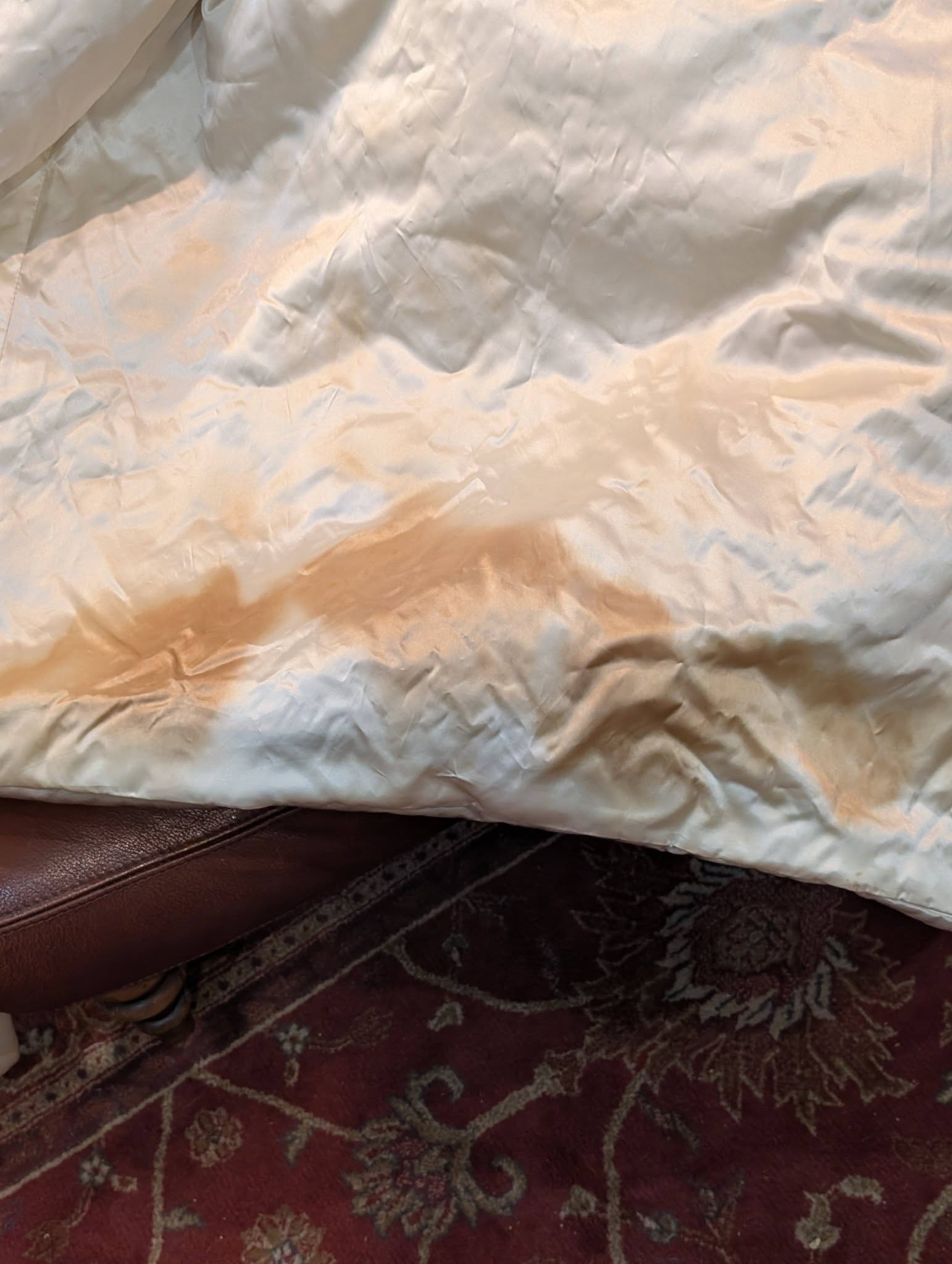 silk12 - Divinely Vintage Interiors Crinkled white tissue paper spread over a dark red patterned rug, with a brown leather edge visible at the bottom.