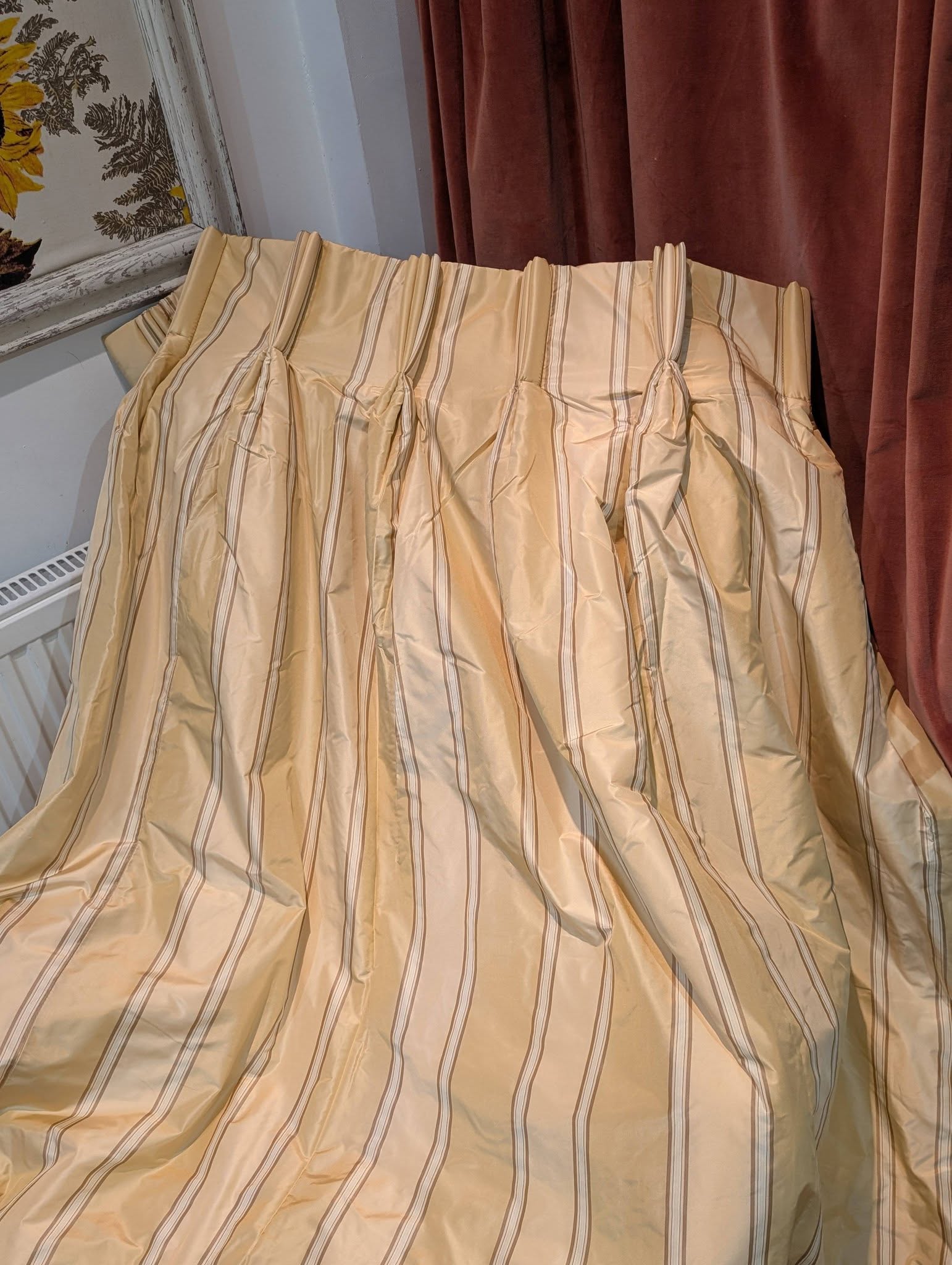 silk5 - Divinely Vintage Interiors Beige striped curtain draped across a corner with brown velvet curtains to the right and a floral wallpaper edge visible on the left.