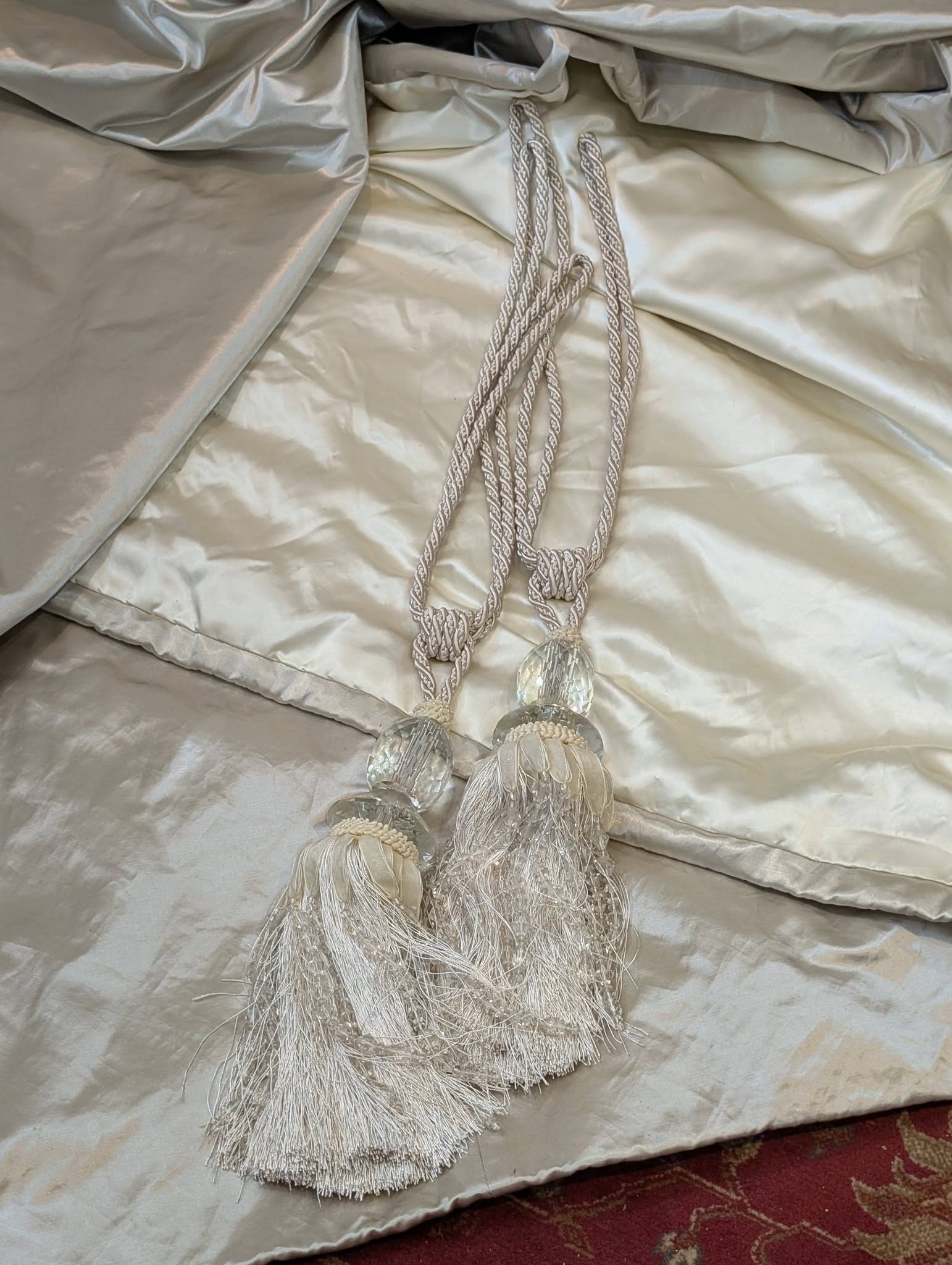 silk8 - Divinely Vintage Interiors Silvery decorative tassels and cords laid on a pale satin blanket.
