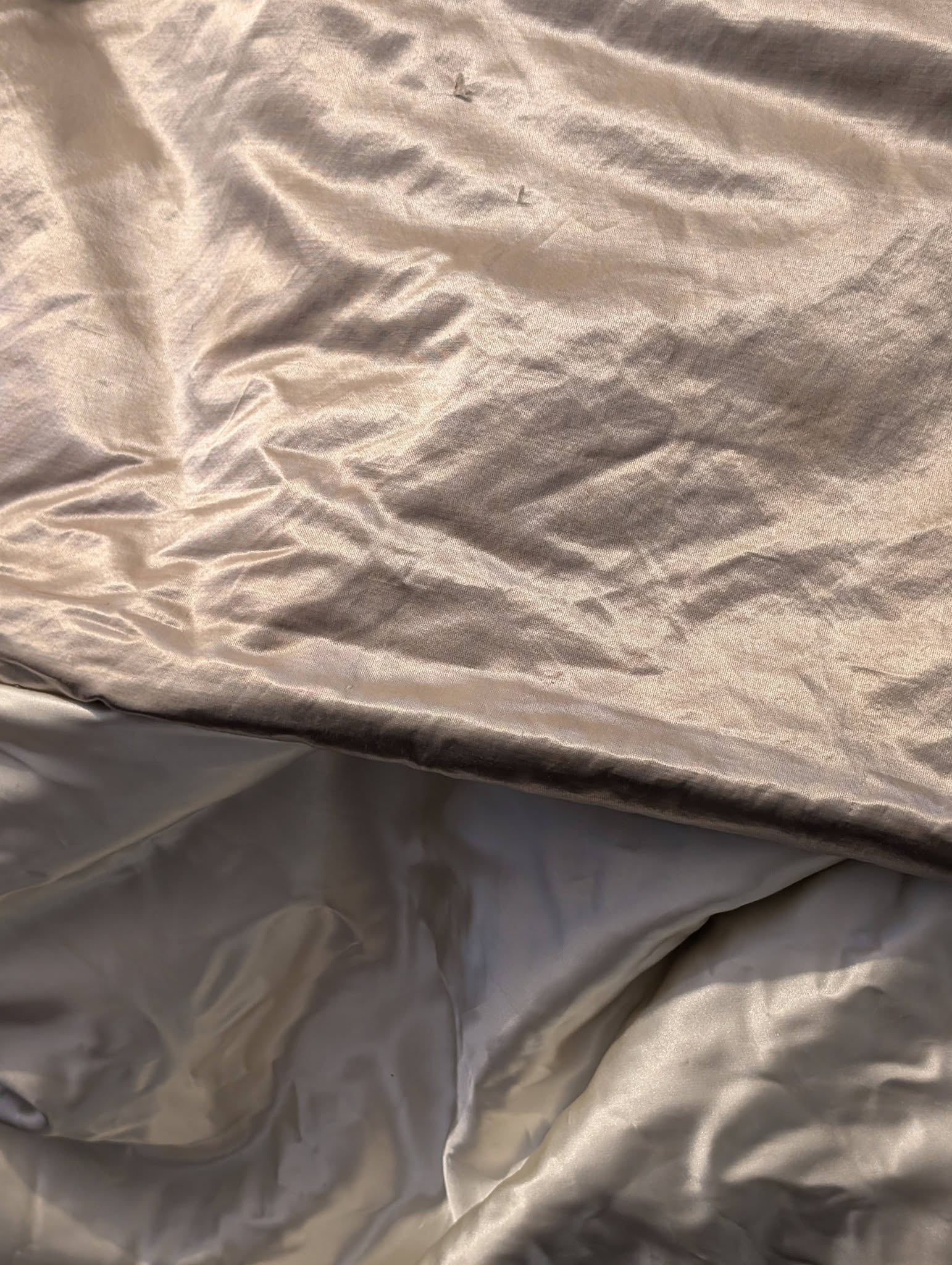 silk9 - Divinely Vintage Interiors Close-up of wrinkled light-beige fabric, likely satin or silk bedding material