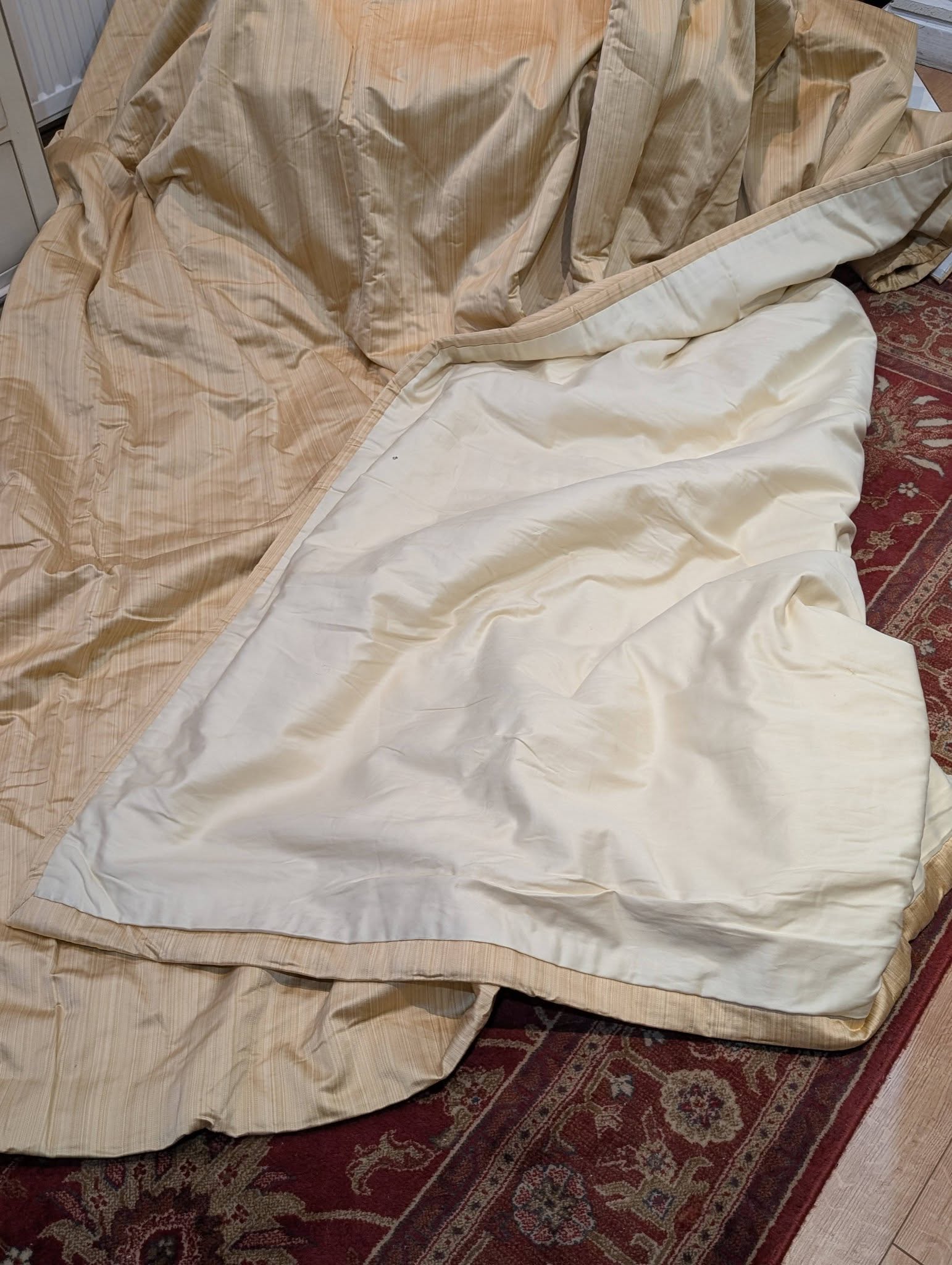 single4 - Divinely Vintage Interiors Beige striped bedspread draped over a bed on a red patterned rug.