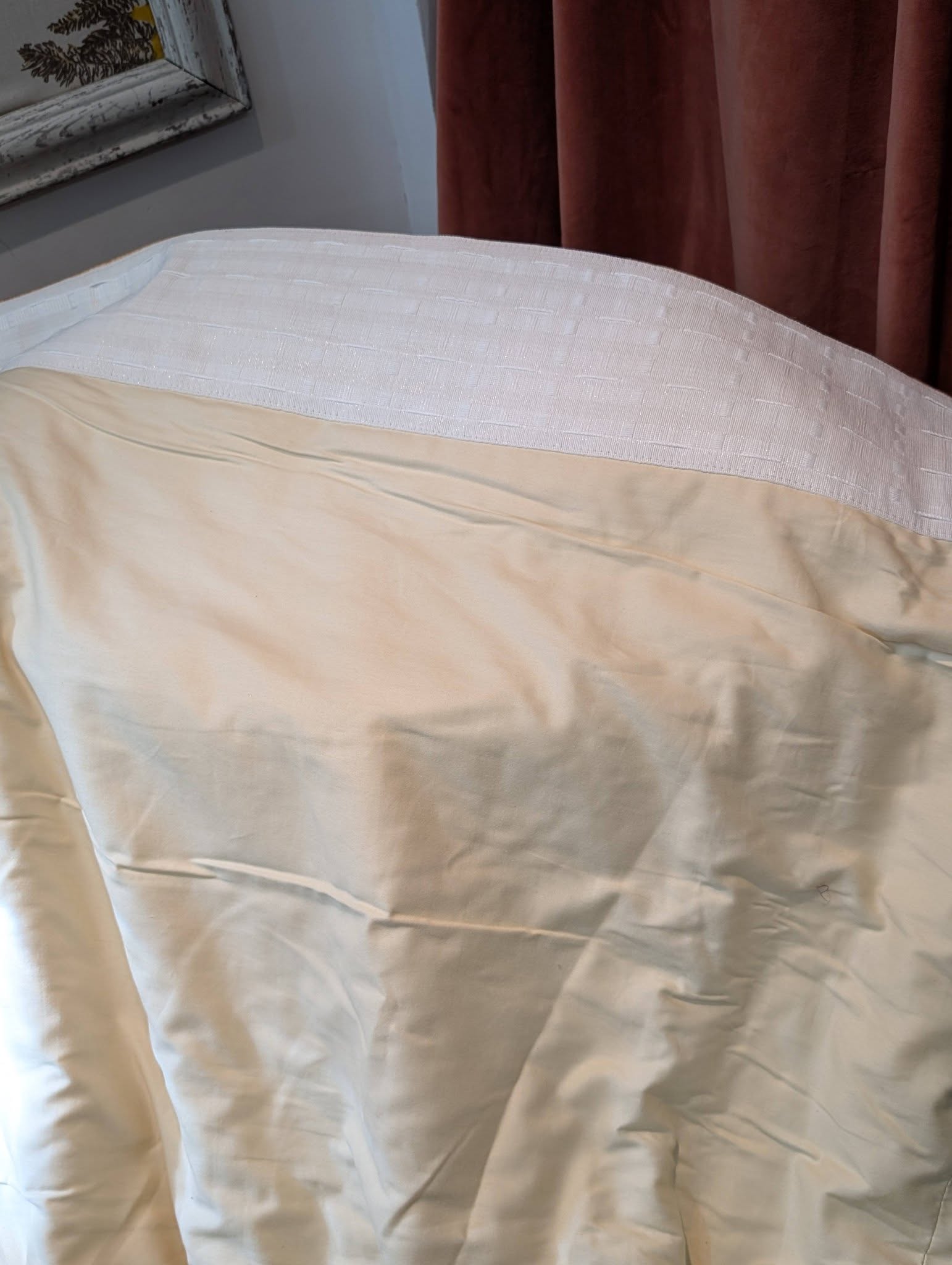 single6 - Divinely Vintage Interiors Close-up of a bed with a white quilted coverlet and cream sheets, brown curtains in the background.
