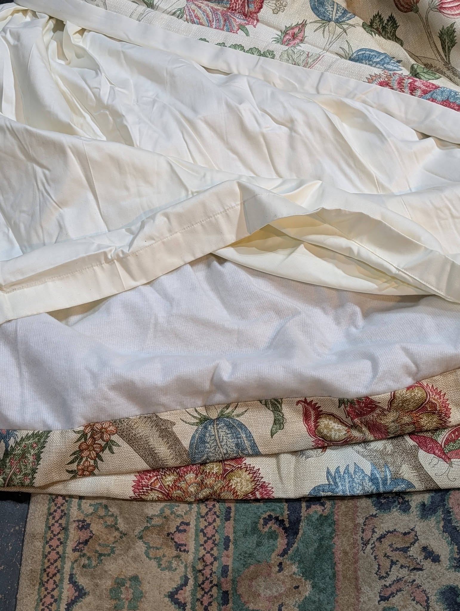 Crinkled white bedsheet draped over a colorful floral quilt.