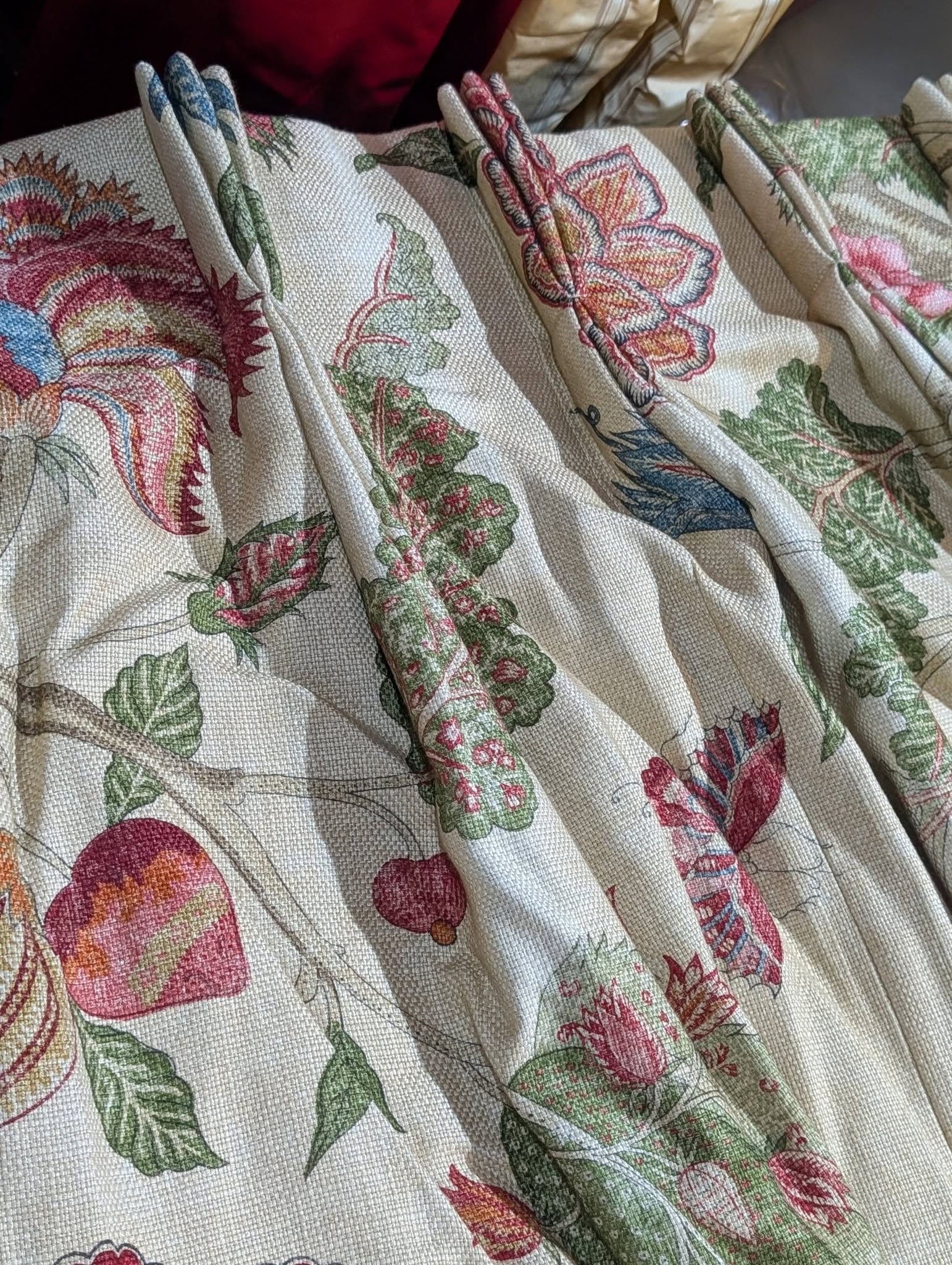 Close-up of beige textured fabric with a colorful botanical print and gathered folds.